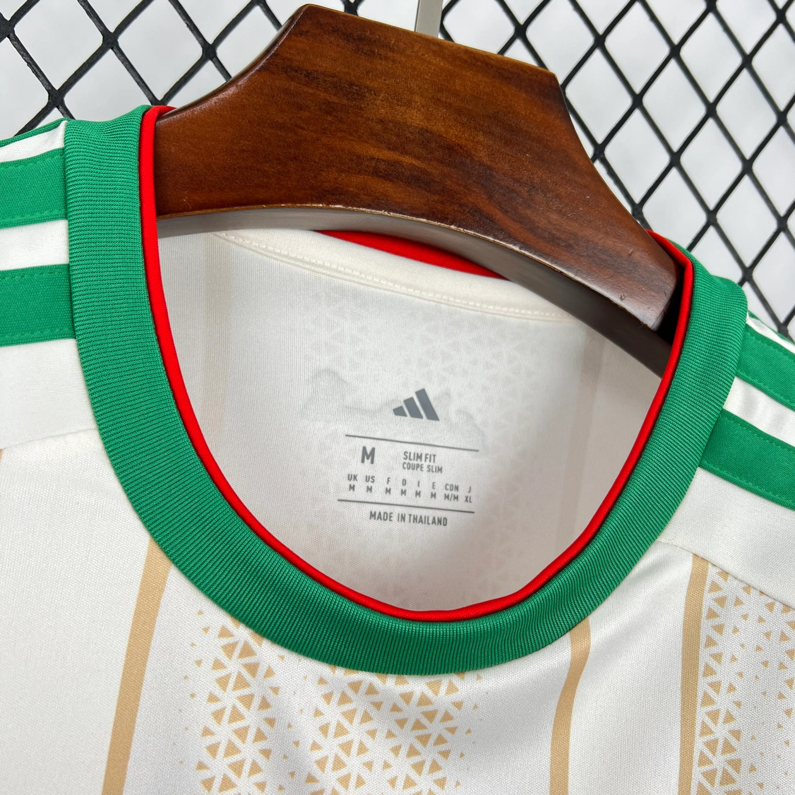 Detalle del cuello redondo verde con borde rojo de la equipación de Argelia 2026.