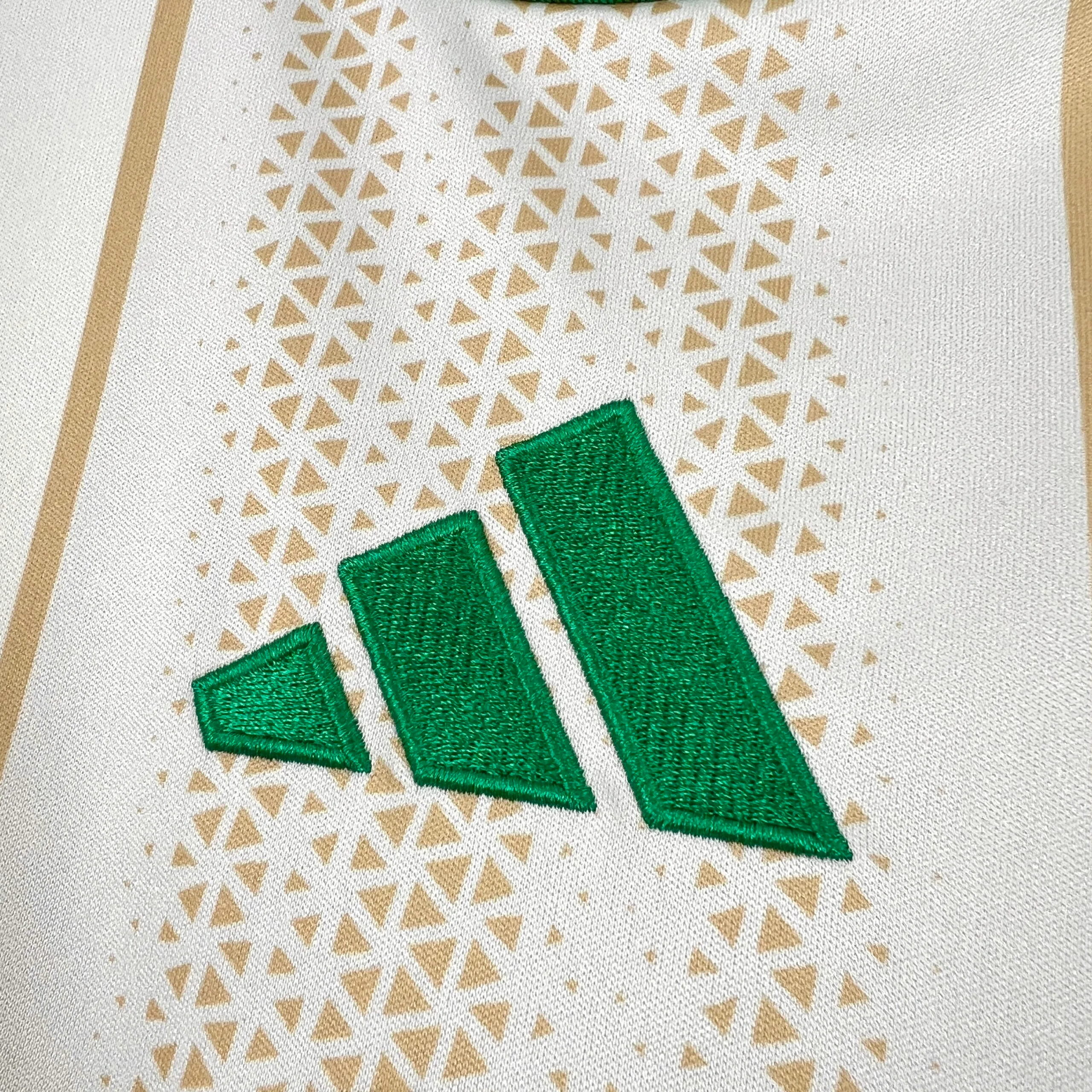Detalle decorativo bordado en color verde sobre el patrón de puntos de la camiseta argelina.