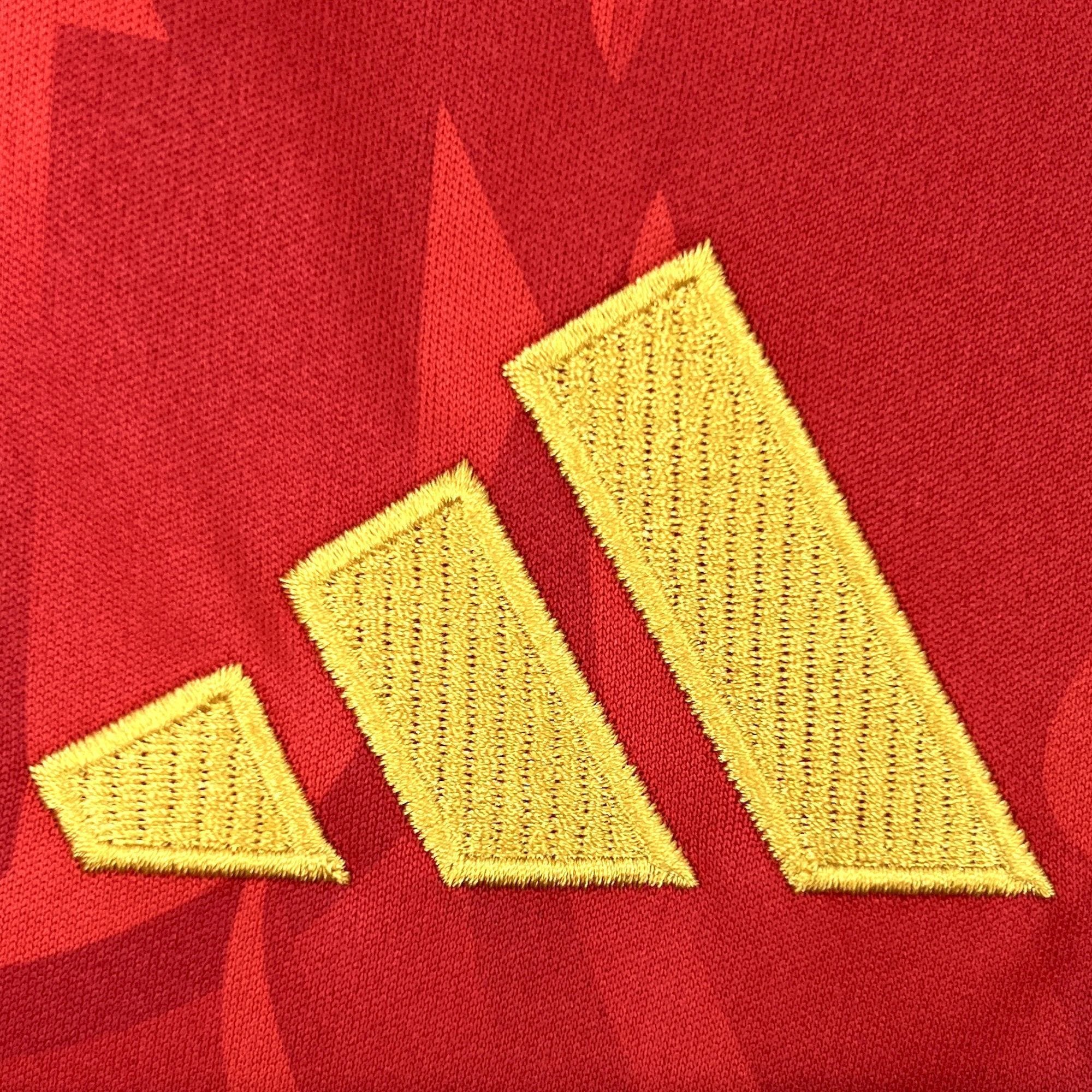 Detalle del bordado decorativo en color amarillo sobre la tela roja con diseño de llamas.