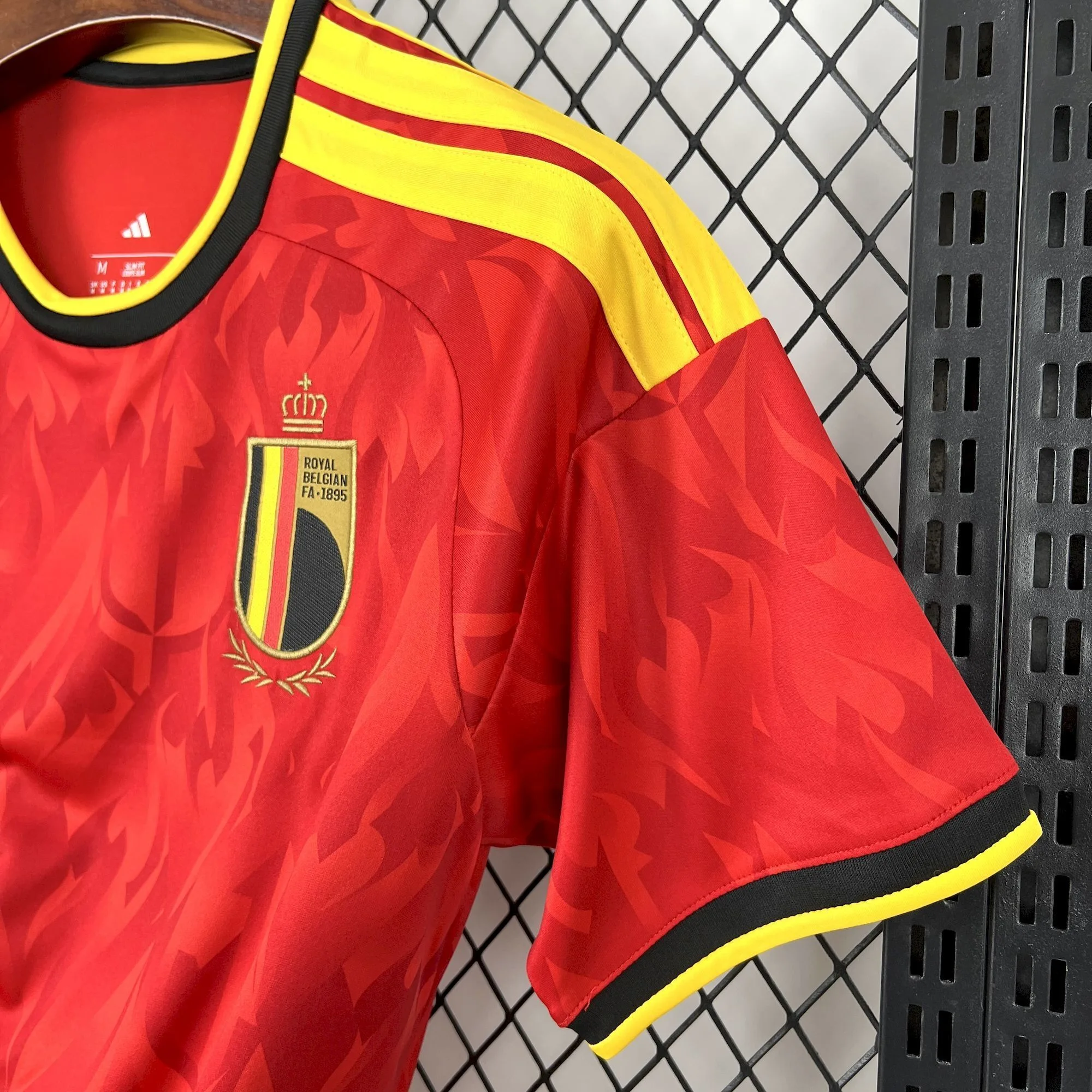 Detalle del hombro y manga de la camiseta de Bélgica con franjas amarillas y ribetes negros.