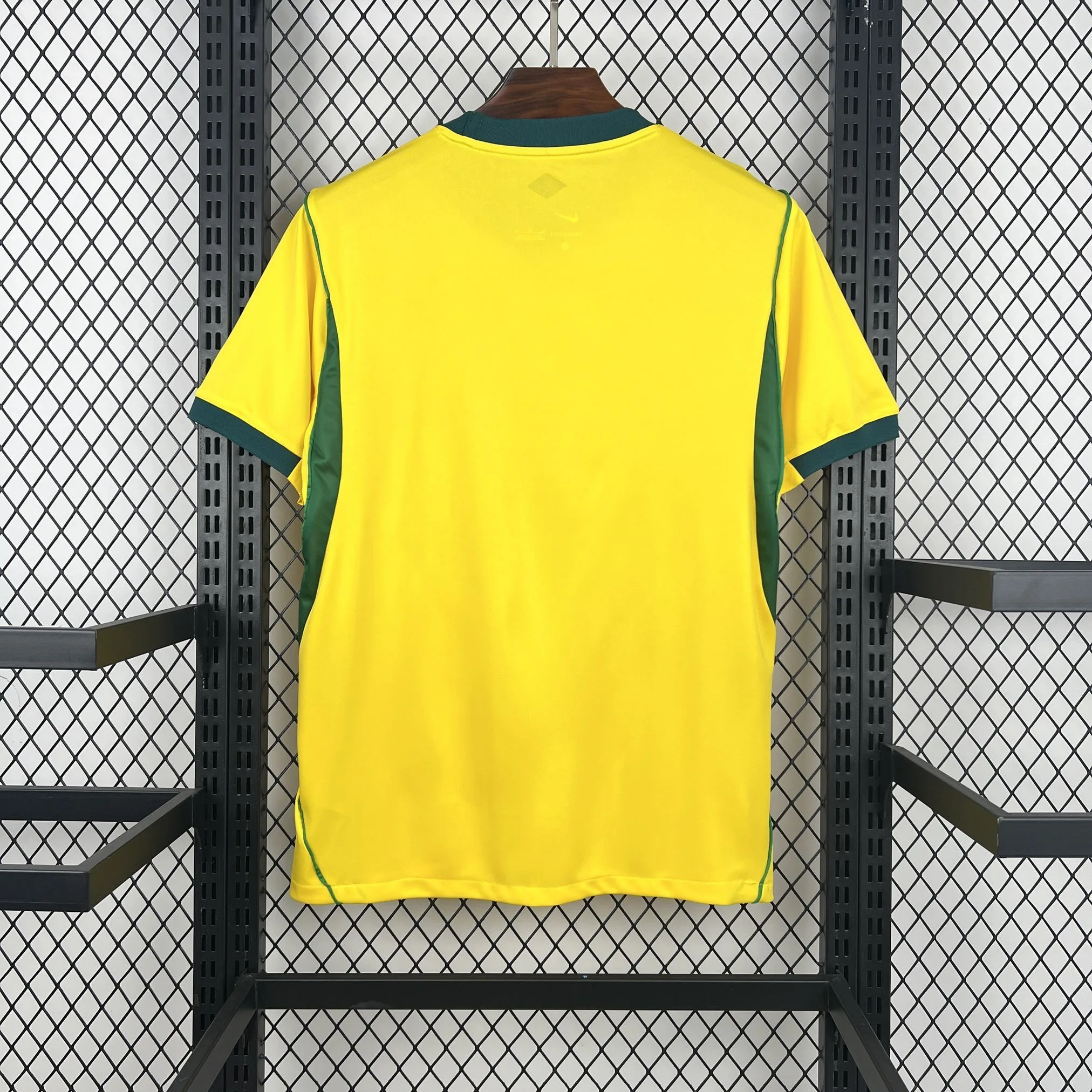 Parte posterior de la camiseta amarilla, resaltando los paneles laterales verdes que se extienden desde las axilas hasta el dobladillo.