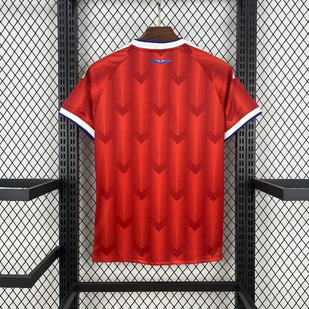 Vista trasera de la camiseta de Chile, mostrando el patrón de flechas en rojo y el emblema del cóndor azul en la nuca.