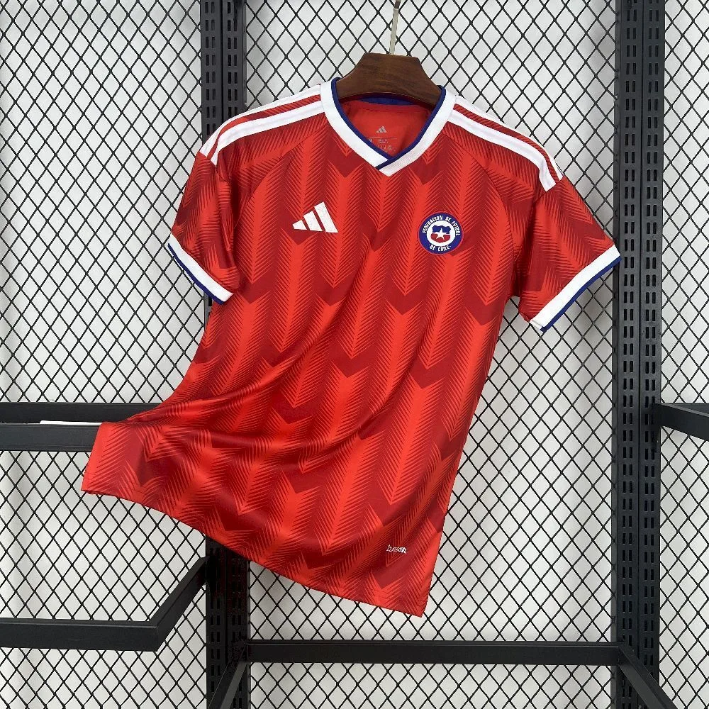 Vista frontal de la camiseta de Chile, con un patrón gráfico de flechas tonales en rojo, cuello en V bicolor y el escudo de la Federación de Fútbol de Chile.