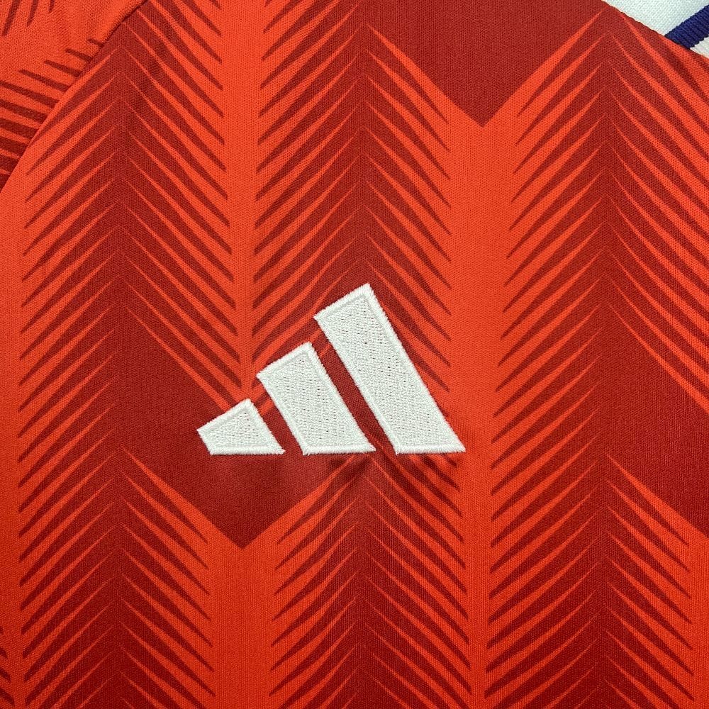 Detalle del logotipo de la marca bordado en blanco sobre el tejido técnico rojo de la selección chilena.