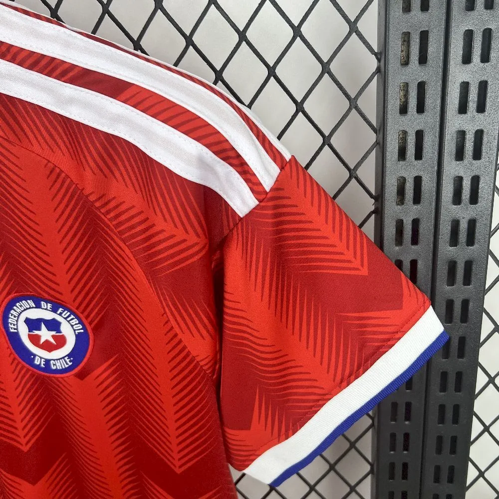 Detalle de la manga de la camiseta chilena, resaltando las franjas blancas en el hombro y el puño elástico en blanco y azul.