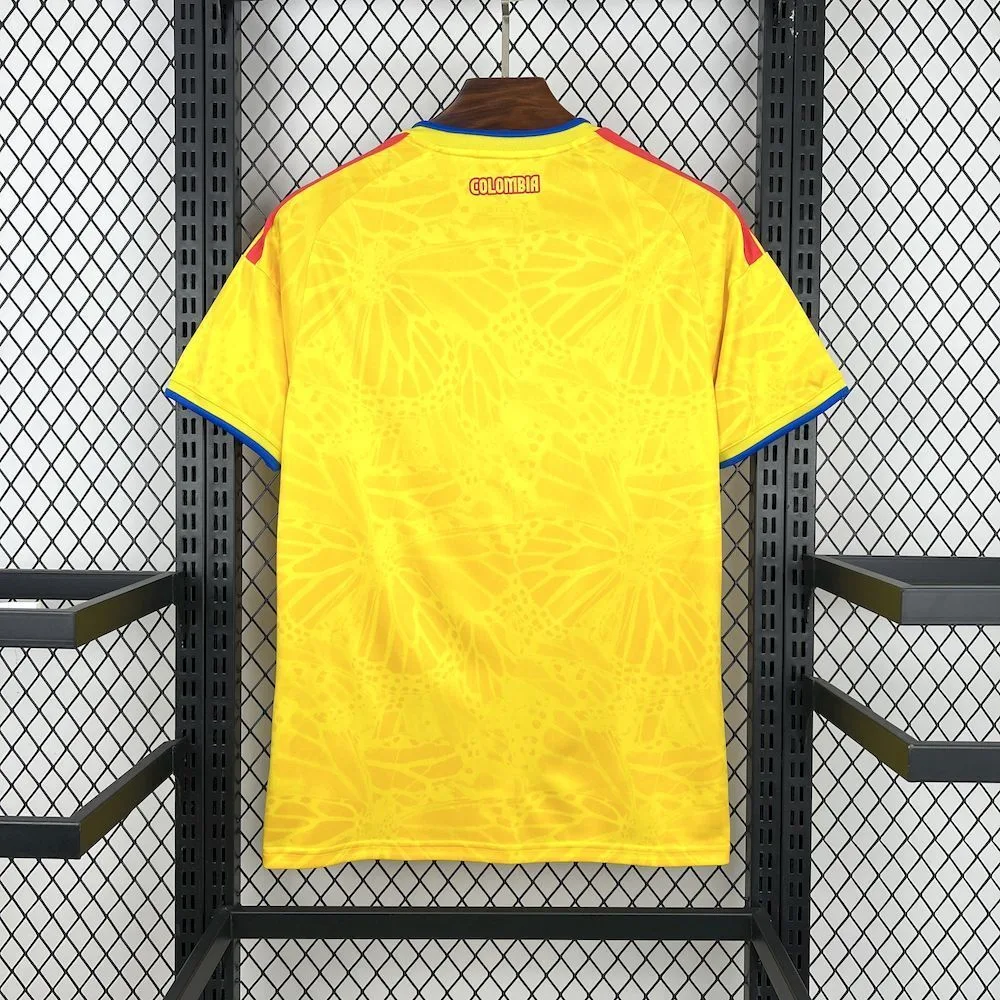Vista trasera de la camiseta de Colombia, destacando el diseño de mariposas en el tejido amarillo y el nombre del país en la nuca.