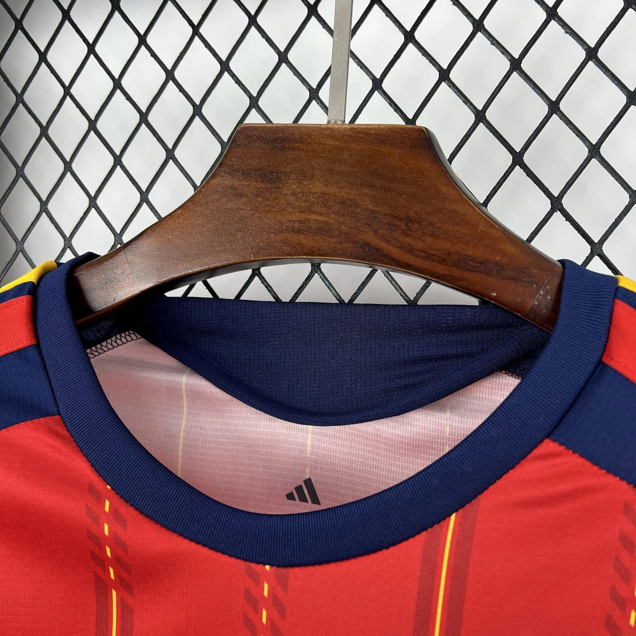 Vista del cuello redondo azul marino de la camiseta de España 2026 con detalles de la talla en el interior y diseño de franjas verticales amarillas.