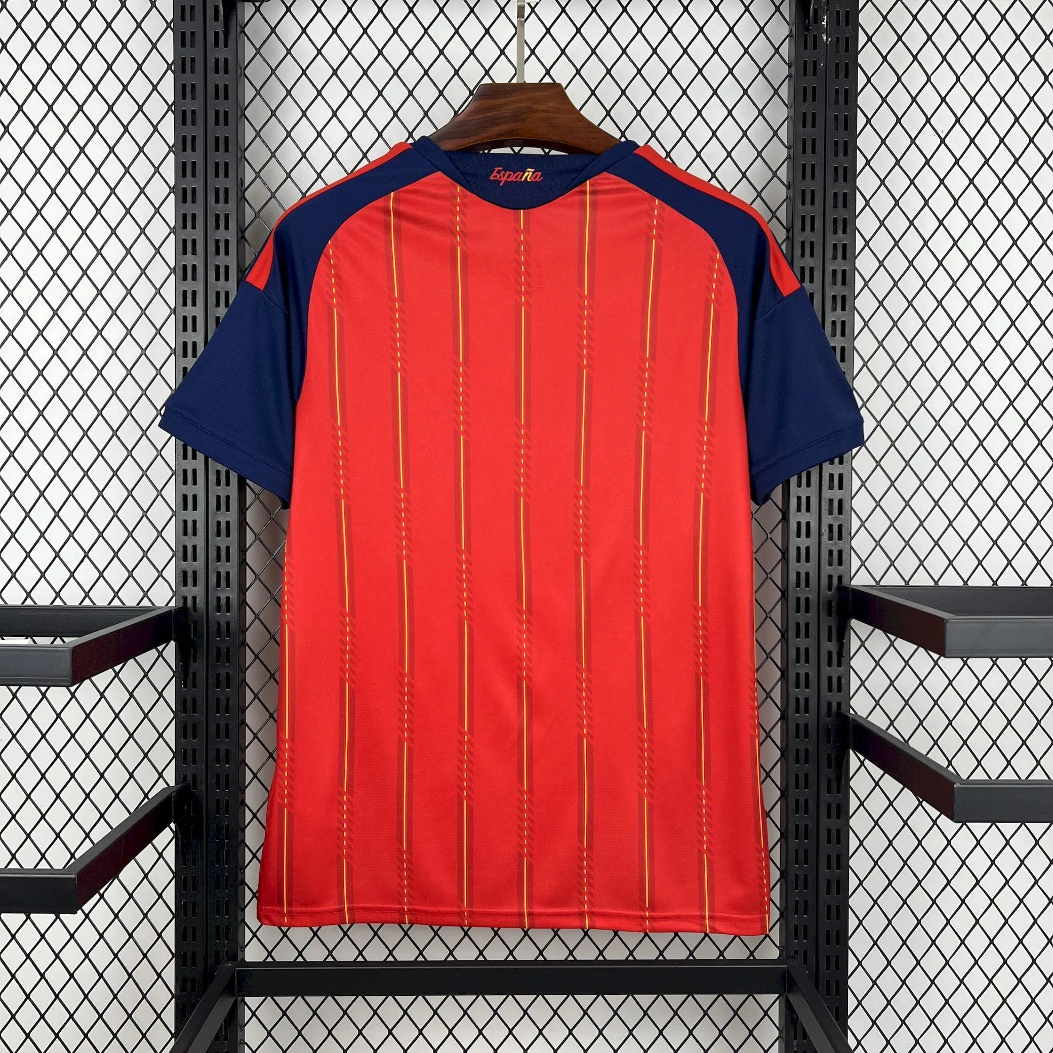 Perspectiva completa de la espalda de la camiseta de España 2026, mostrando el patrón continuo de franjas verticales y las mangas en contraste azul marino.