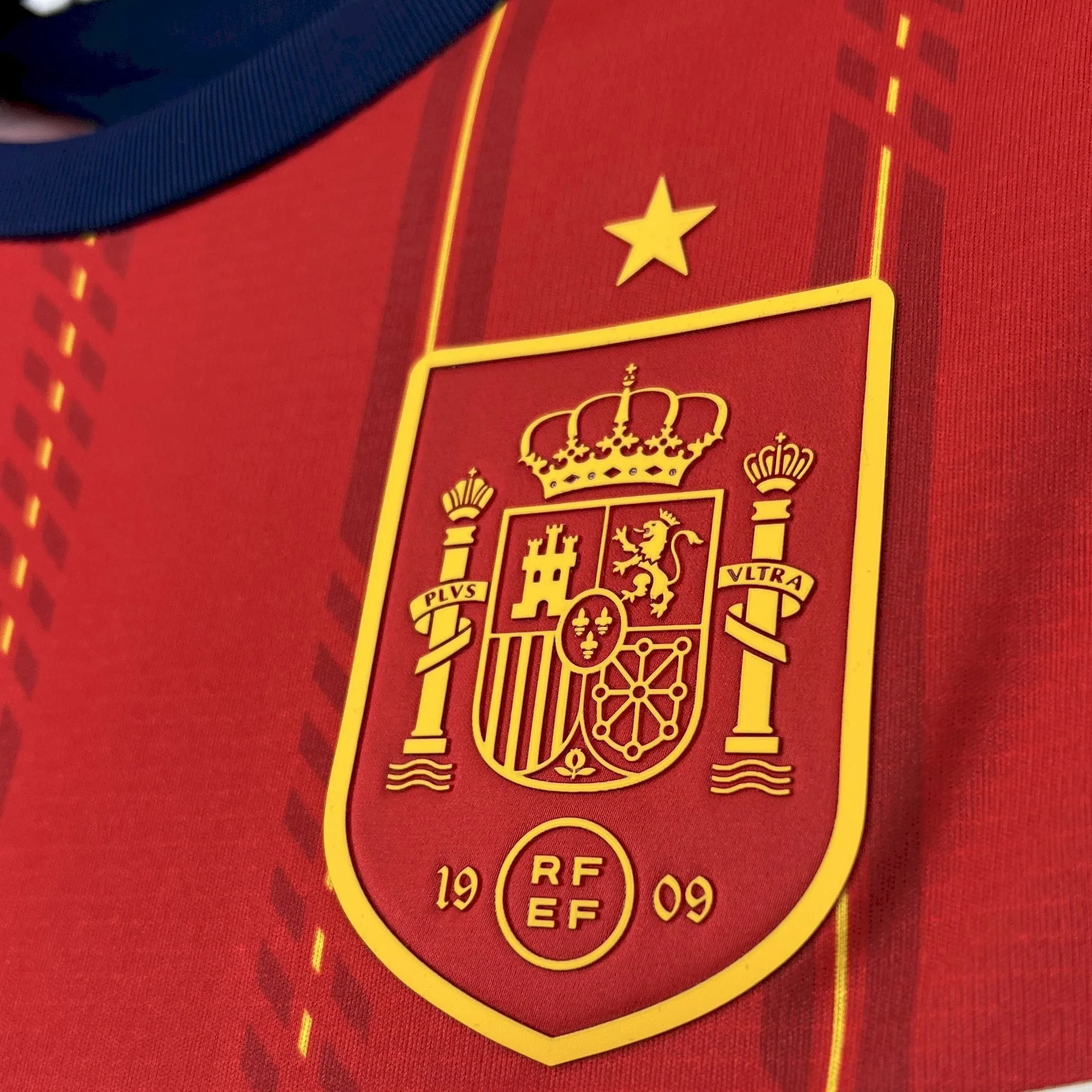 Detalle en relieve del escudo de la selección española y estrella de campeón sobre el tejido rojo de la camiseta para el Mundial 2026.