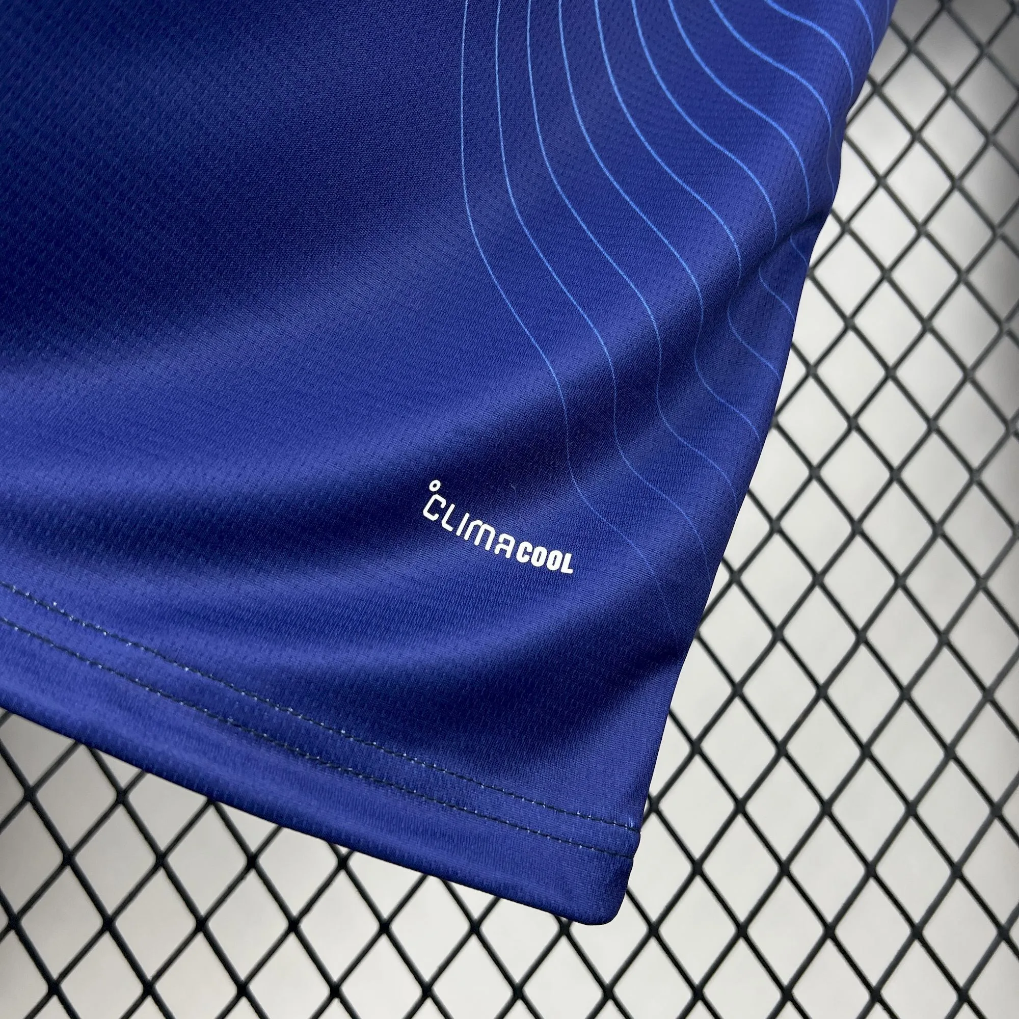 Primer plano del diseño de líneas curvas degradadas en la parte inferior de la camiseta azul de Japón.