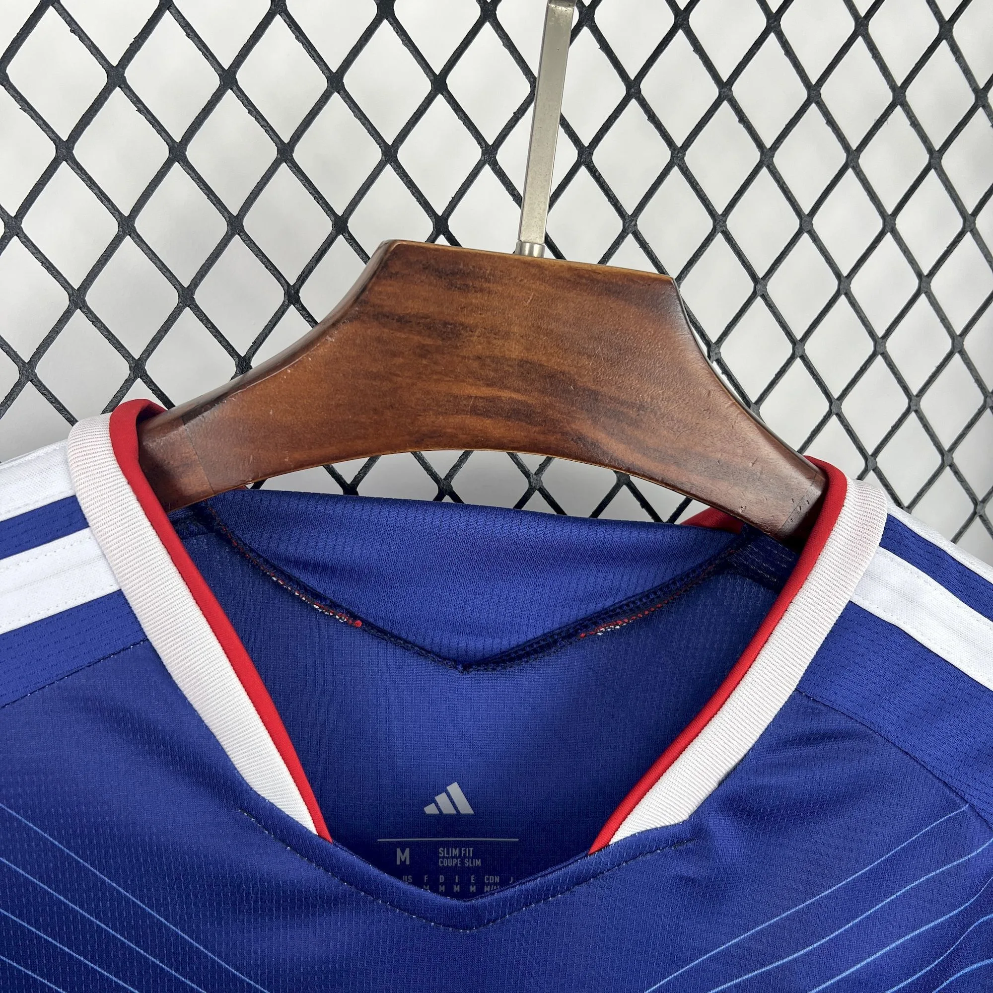 Detalle del cuello en "V" con ribetes blancos y rojos de la camiseta de fútbol de Japón.