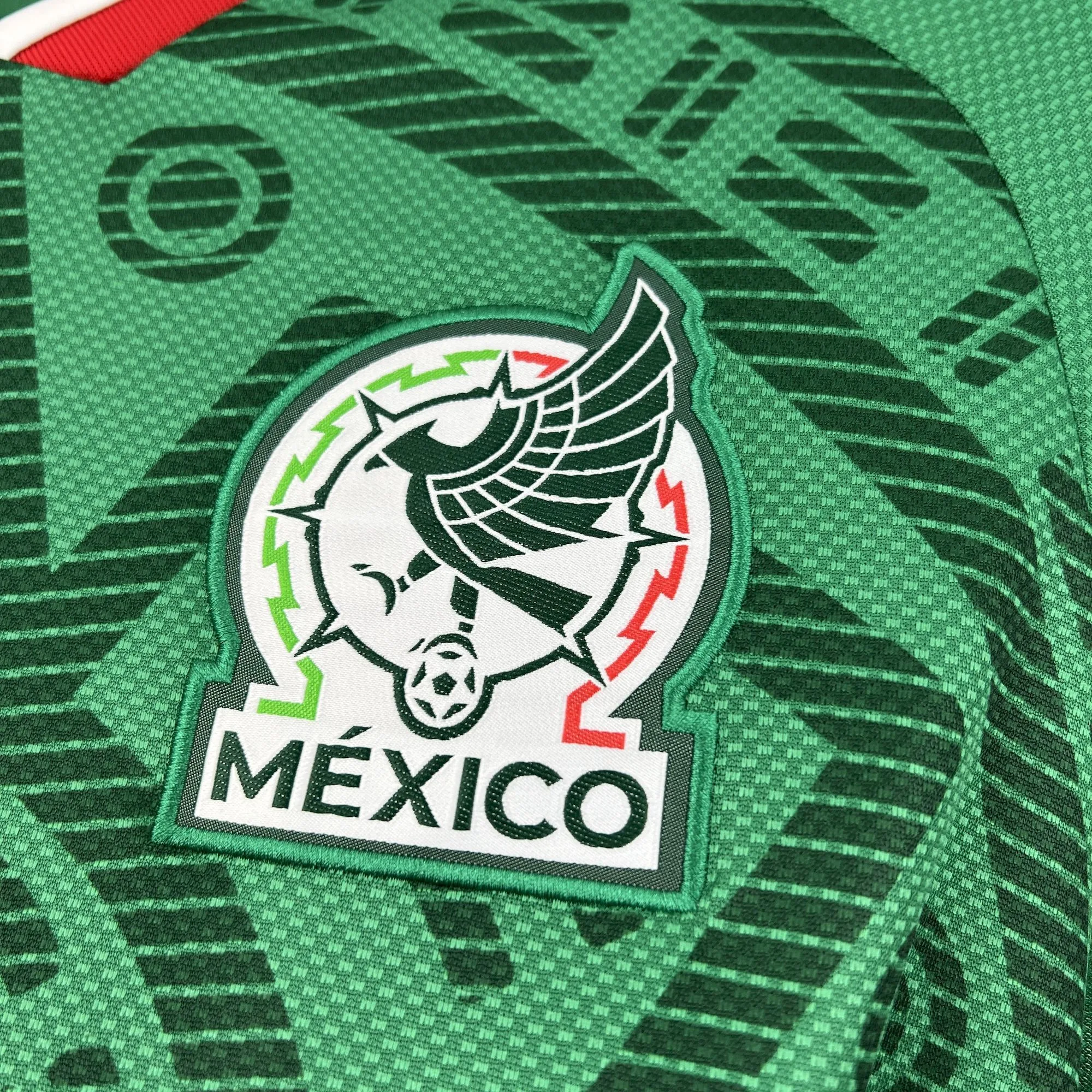 Escudo de la selección de fútbol de México bordado en verde, blanco y rojo sobre el diseño temático de la camiseta para el Mundial 2026.