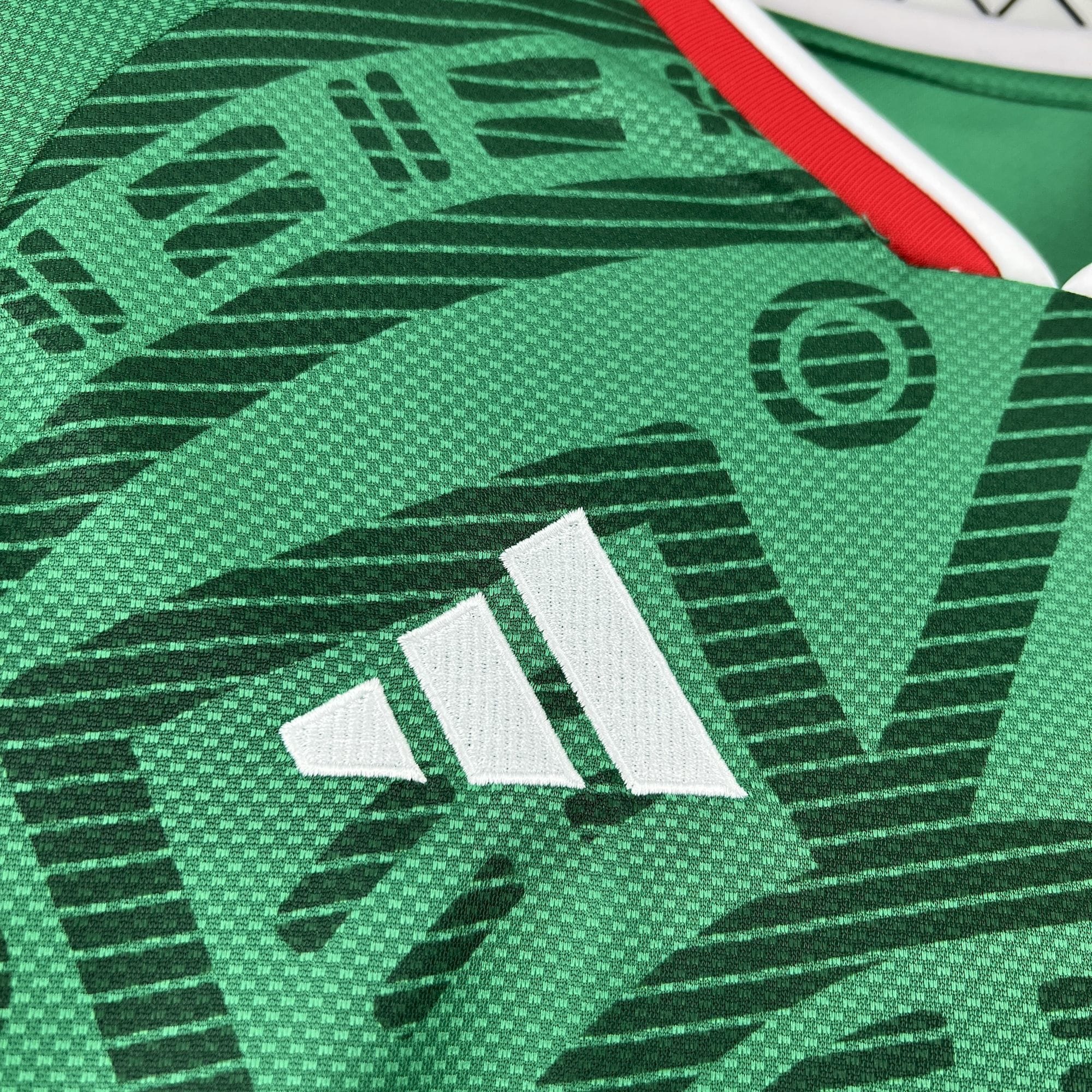 Detalle del logotipo bordado en blanco sobre el patrón gráfico de inspiración azteca en el pecho de la camiseta de México 2026.