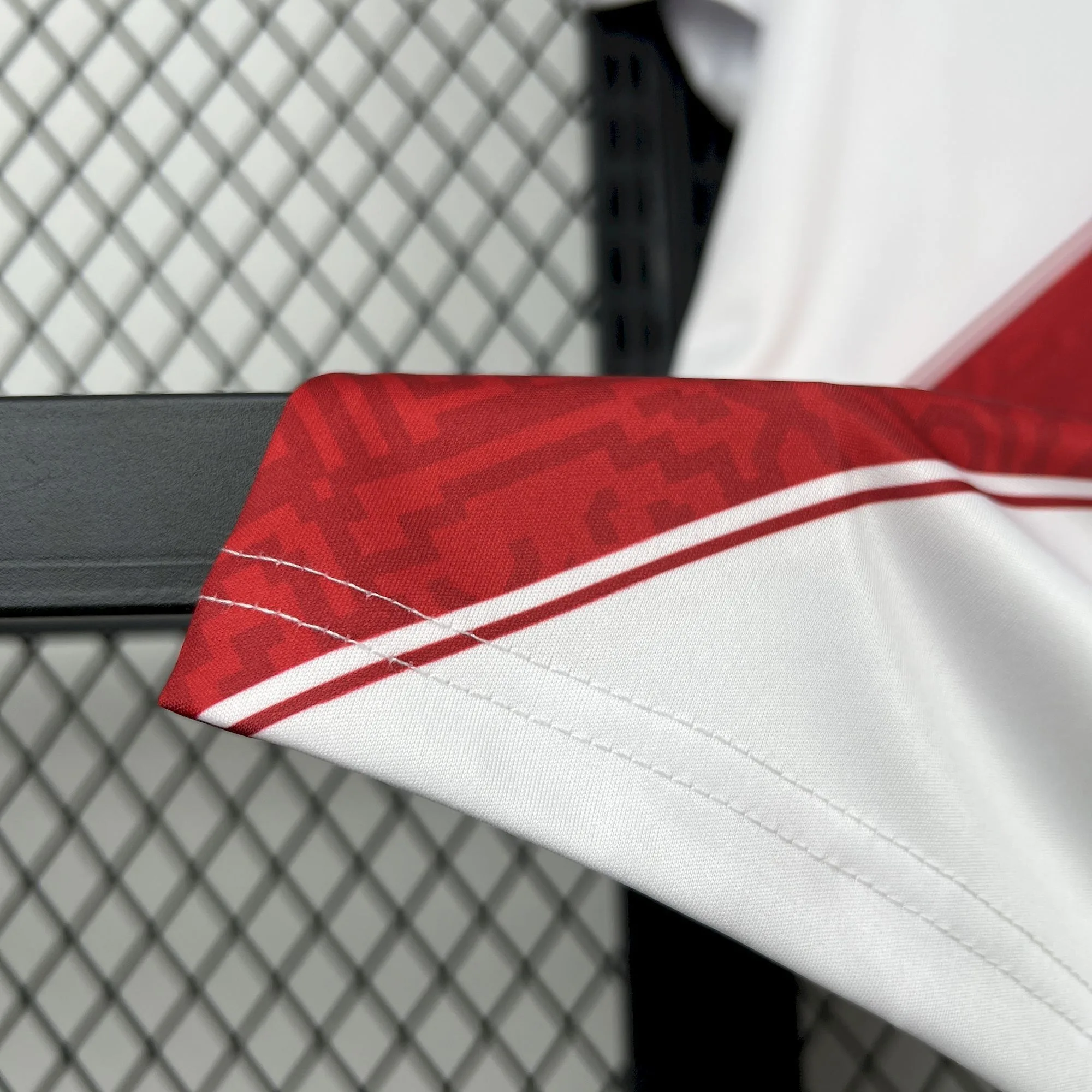 Primer plano del tejido técnico y el acabado de la franja roja con patrones gráficos de la camiseta de Perú 2026.
