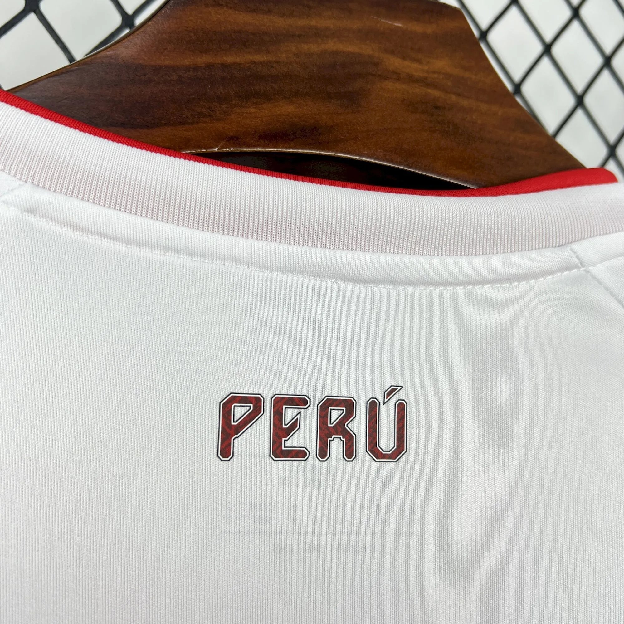 Detalle de la nuca de la camiseta de Perú 2026 con el nombre del país estampado en letras rojas con diseño estilizado.