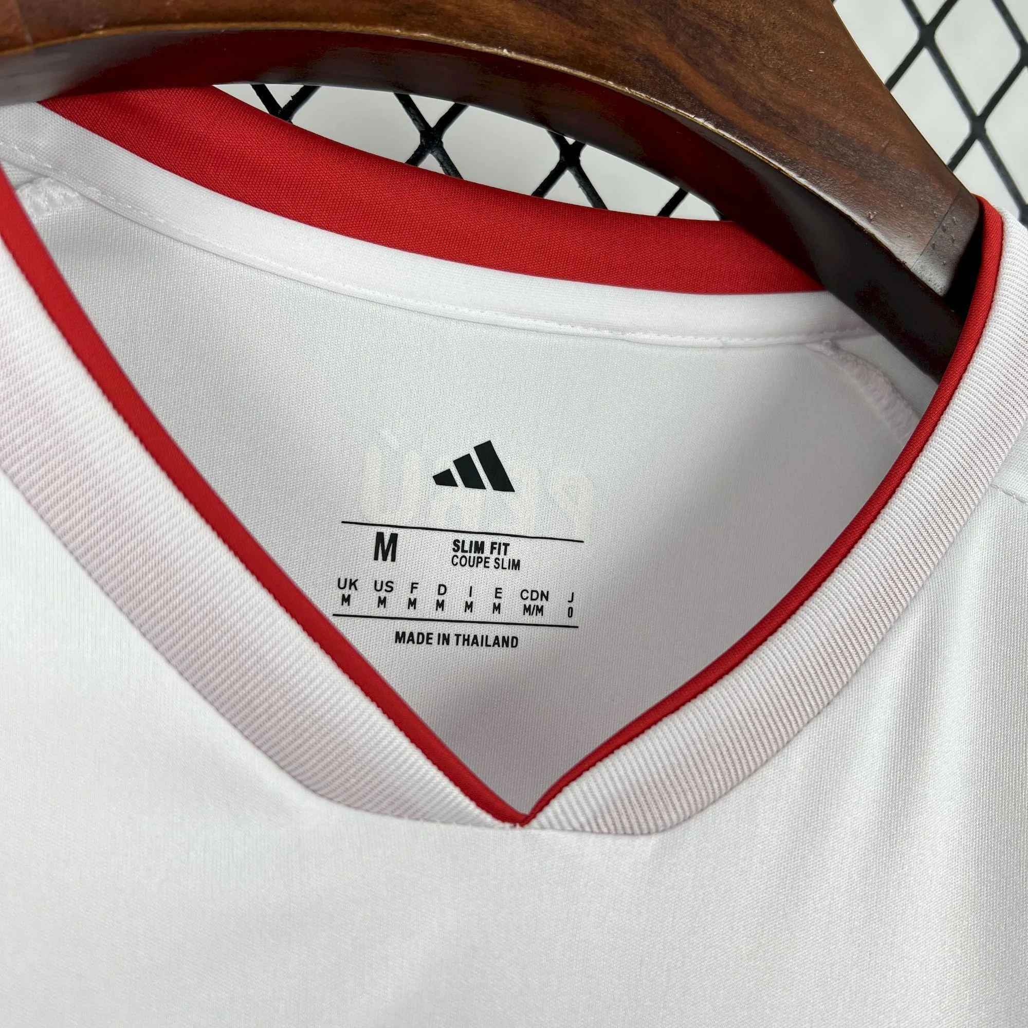 Detalle del interior del cuello en V de la camiseta de Perú 2026 con etiquetas de tallaje M y corte Slim Fit.