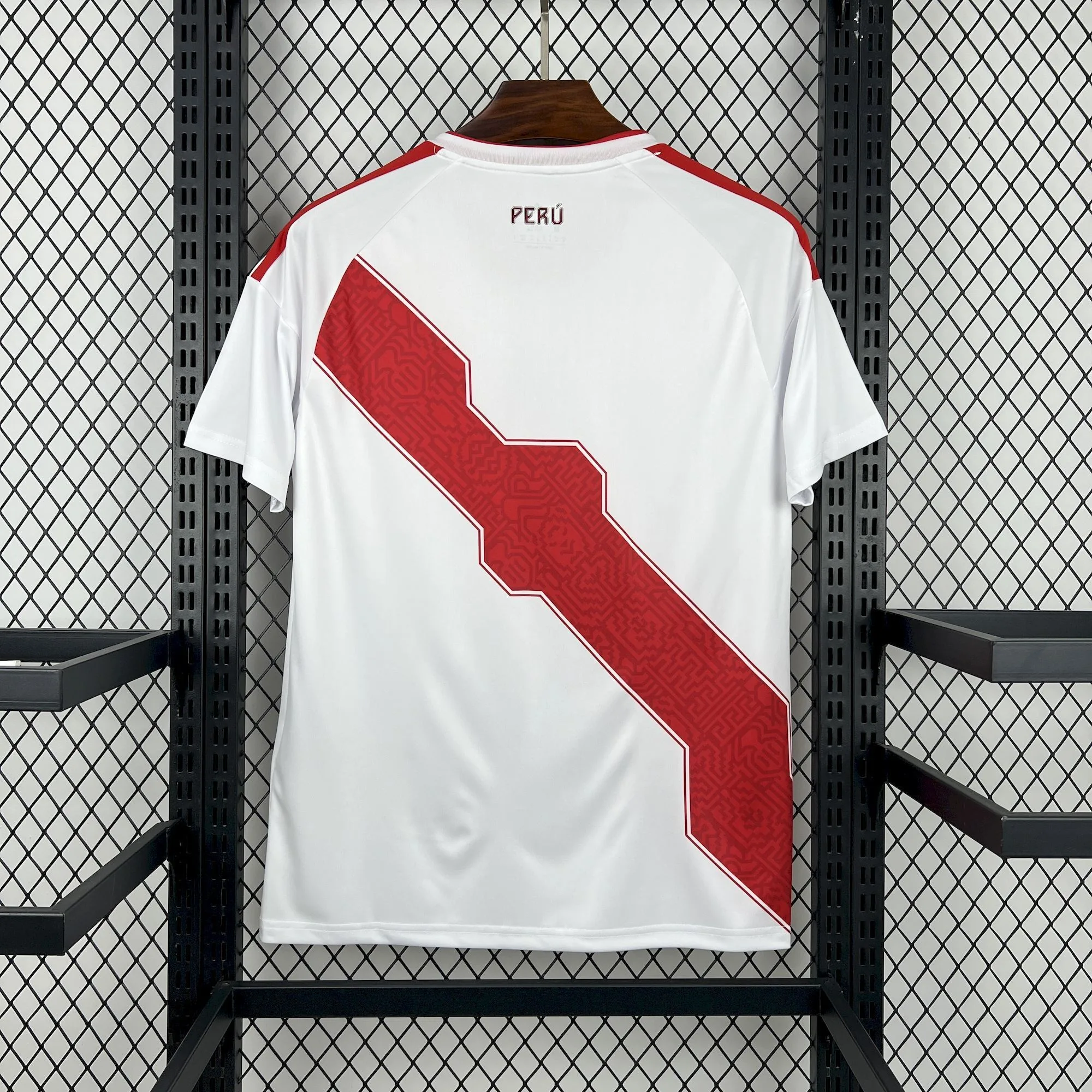 Vista trasera de la camiseta de Perú para el Mundial 2026, con franja roja diagonal y el nombre del país impreso en la nuca.