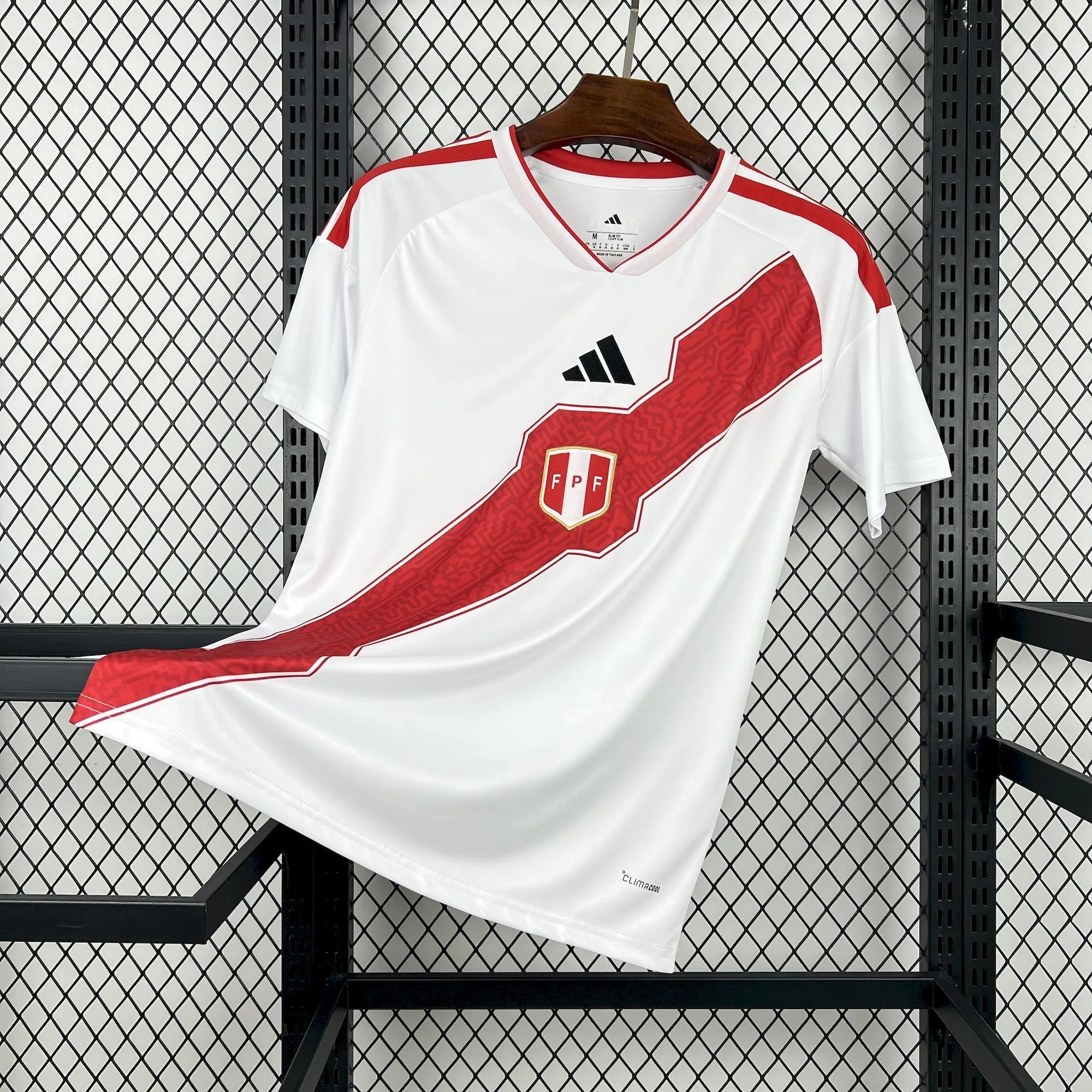 Camiseta de fútbol de la selección de Perú para el Mundial 2026, blanca con franja diagonal roja y patrón gráfico detallado.