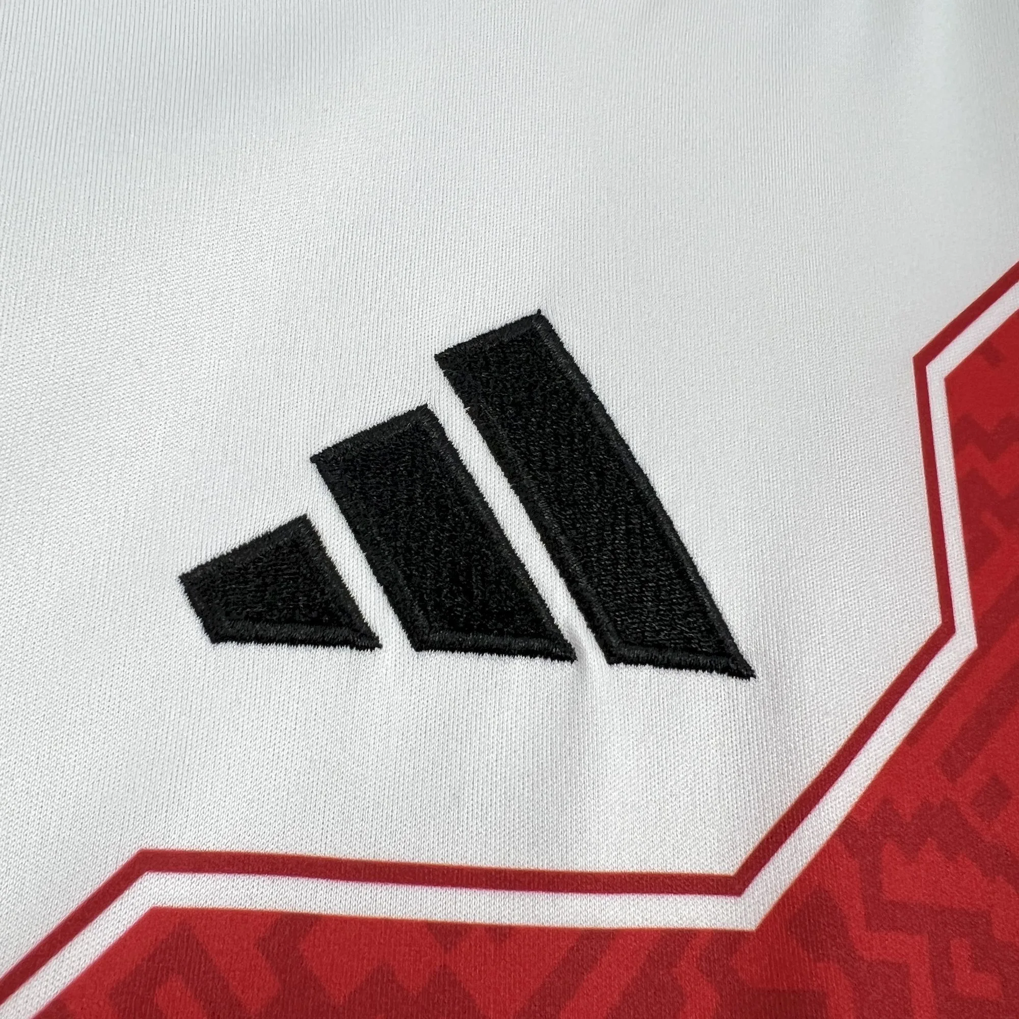 Detalle del logotipo bordado en color negro sobre el tejido blanco del pecho de la camiseta de Perú para el Mundial 2026.