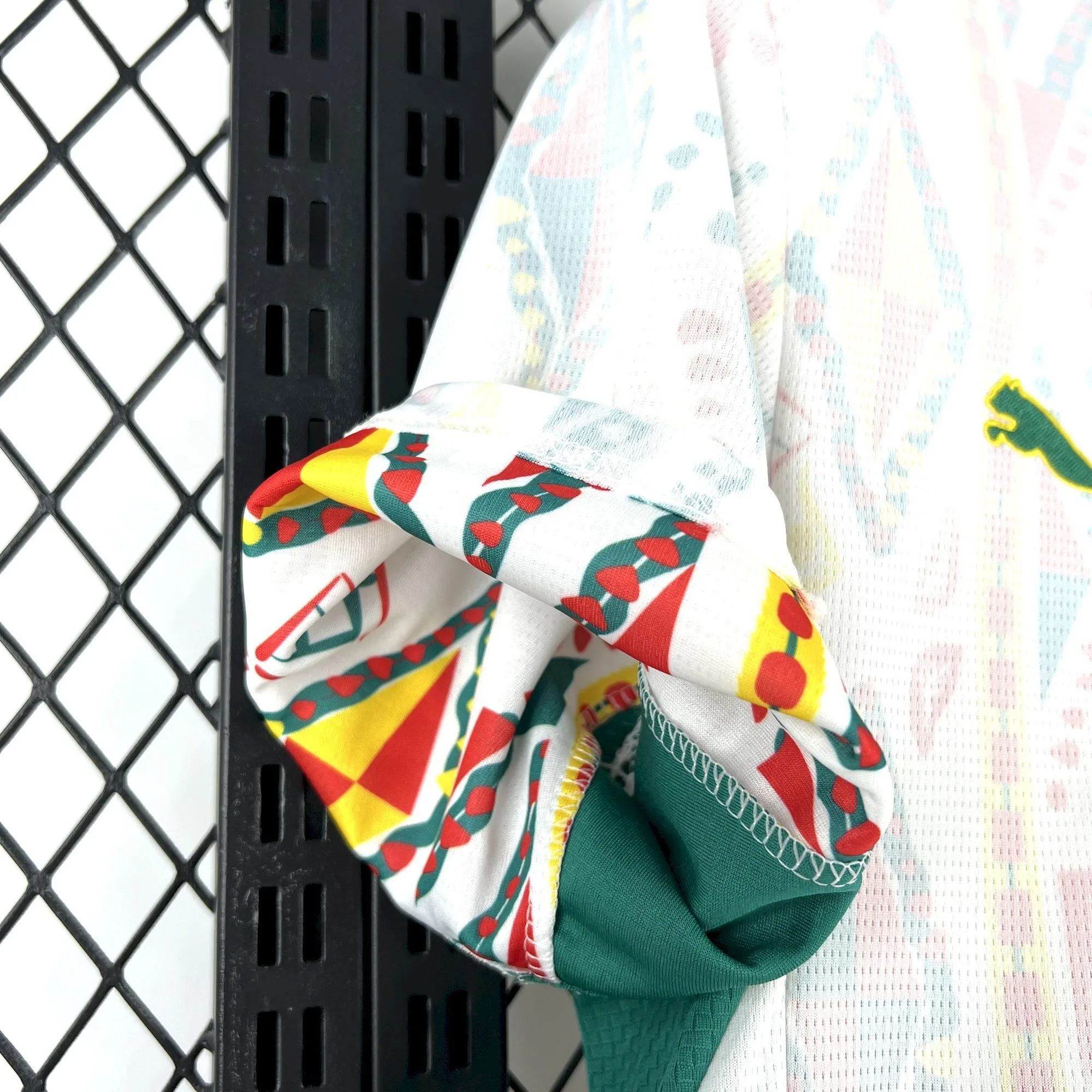 Detalle de la manga blanca con patrón de arte tradicional africano en colores verde, amarillo y rojo.