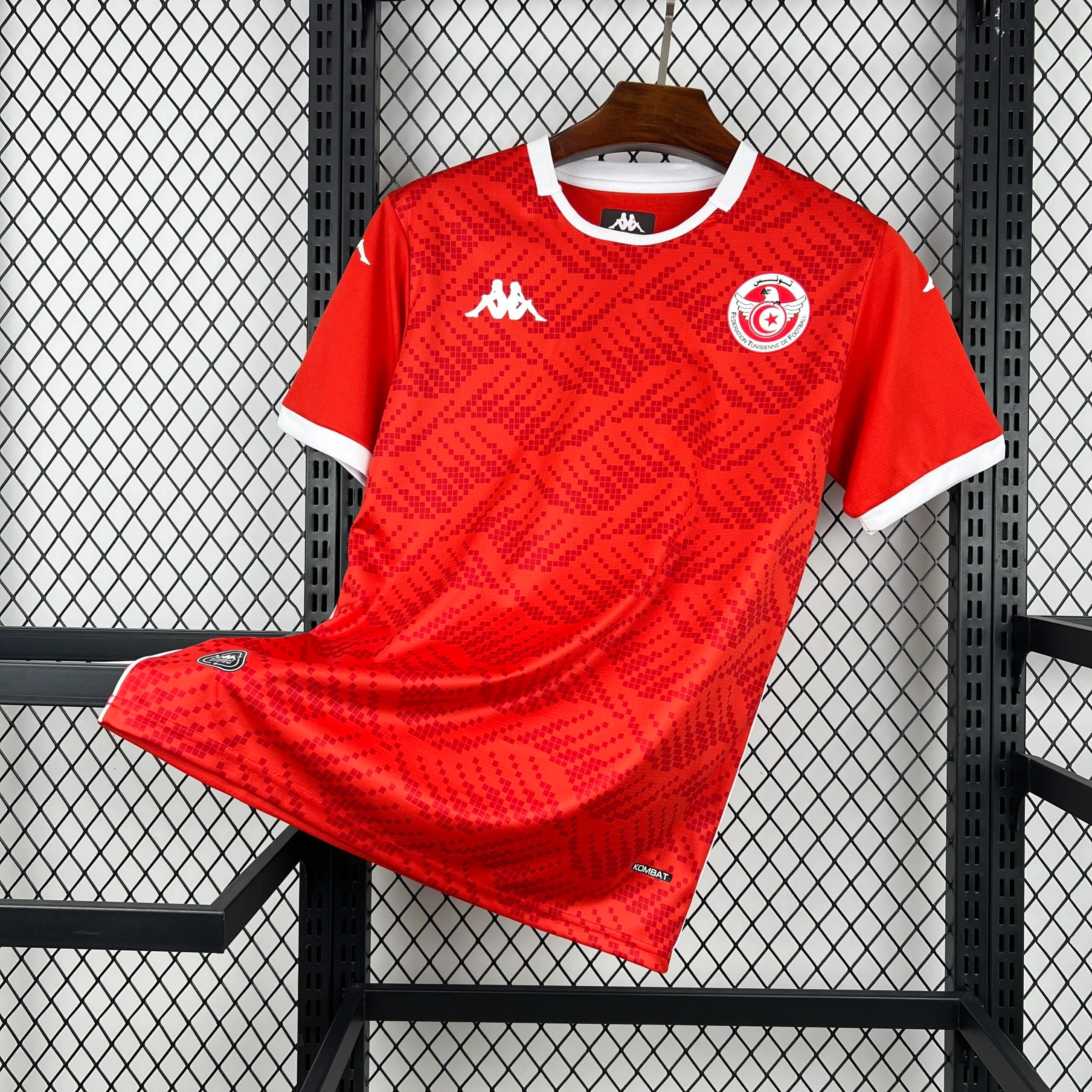 Camiseta de la selección de Túnez en color rojo con un patrón geométrico tonal de diamantes en el frente, cuello redondo y bordes de las mangas en contraste blanco, incluyendo el escudo de la federación en el pecho.