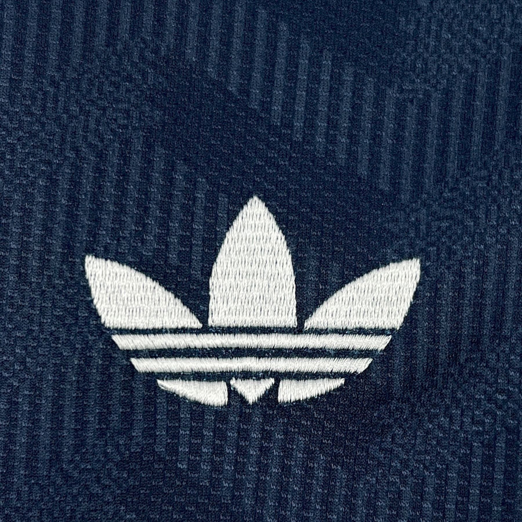 Detalle de elemento decorativo bordado en color blanco sobre el patrón gráfico de la camiseta visitante alemana.