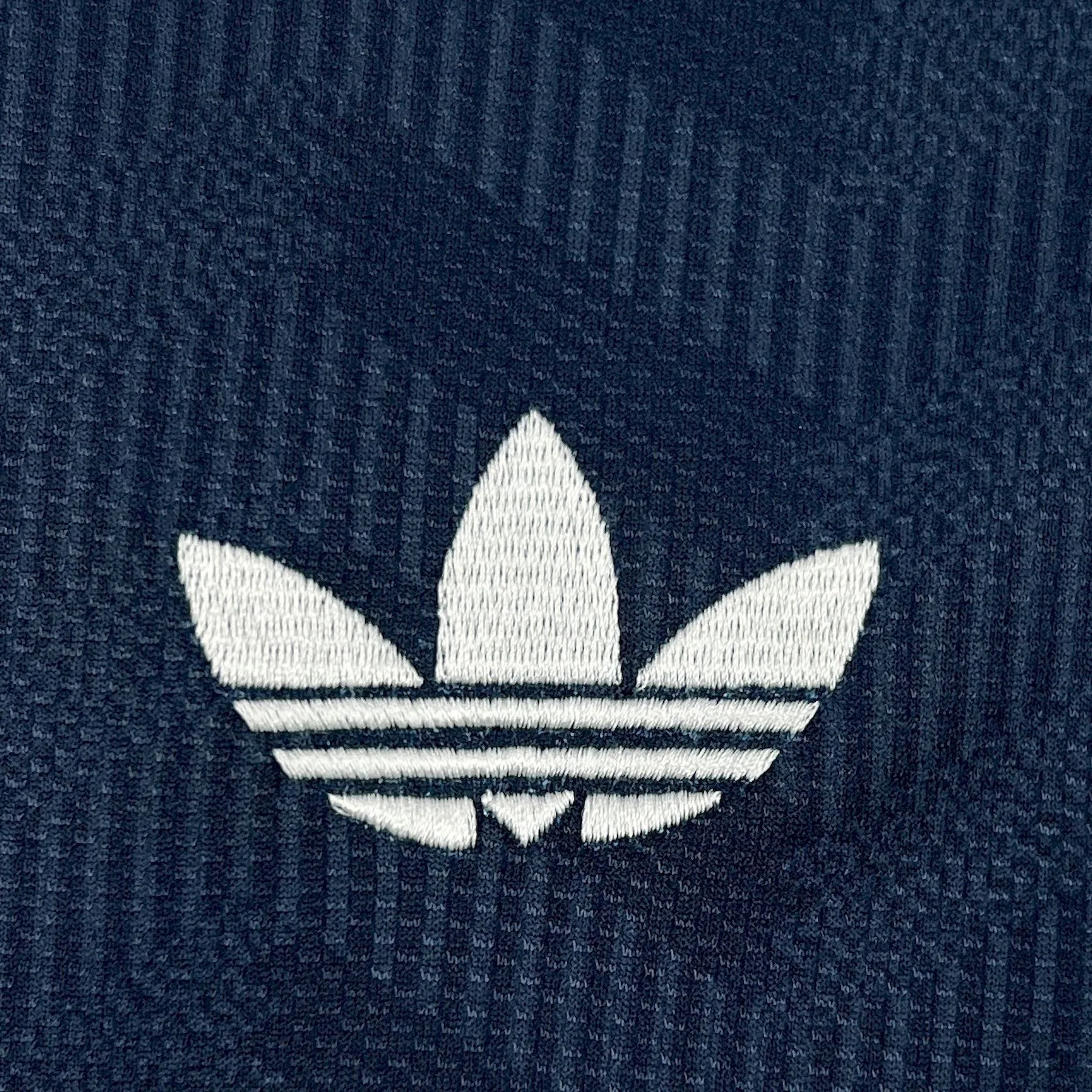 Detalle de elemento decorativo bordado en color blanco sobre el patrón gráfico de la camiseta visitante alemana.