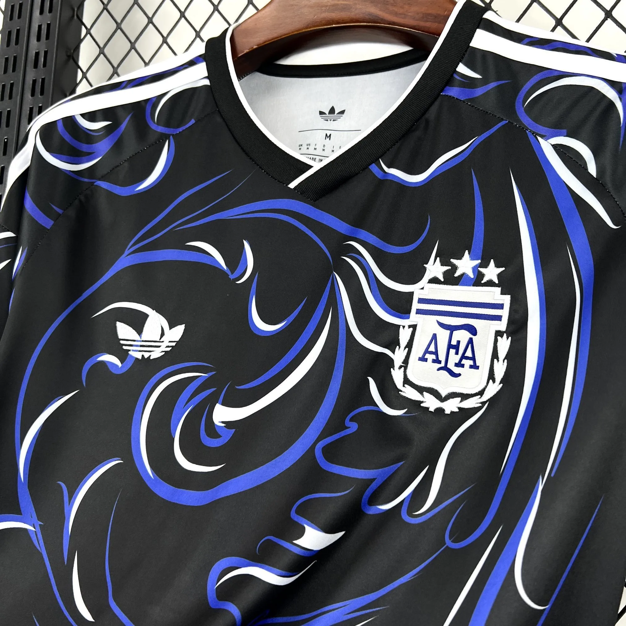 Primer plano del escudo de la AFA bordado en dorado sobre el tejido azul con textura de la camiseta.