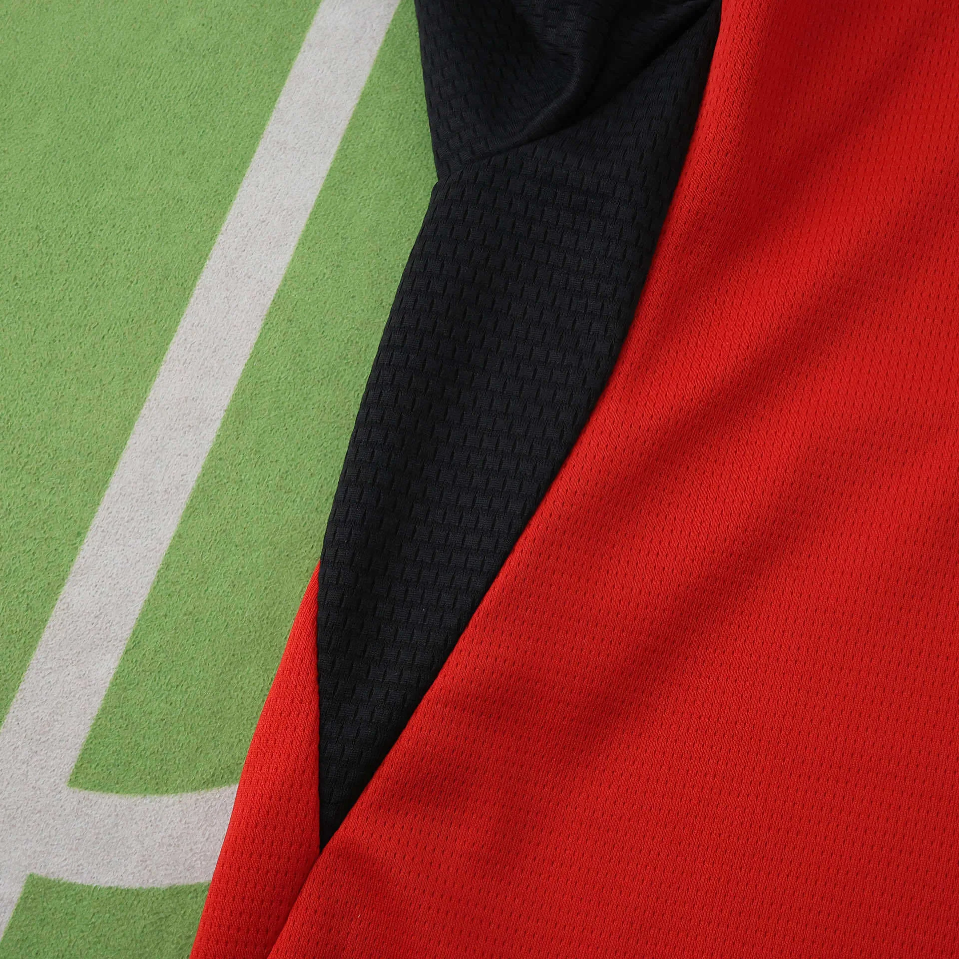 Detalle de la inserción lateral negra sobre el tejido rojo microperforado de la camiseta de Austria.