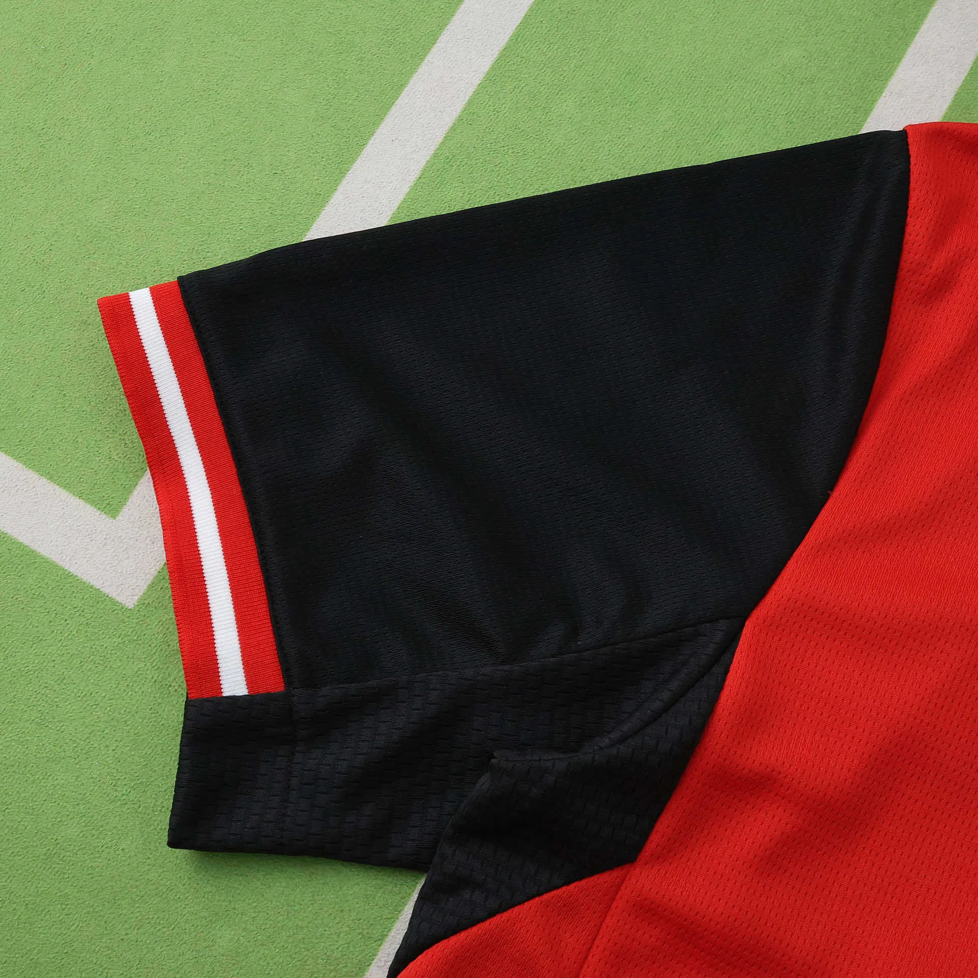 Primer plano del puño de la manga negra con elástico tricolor en rojo y blanco.