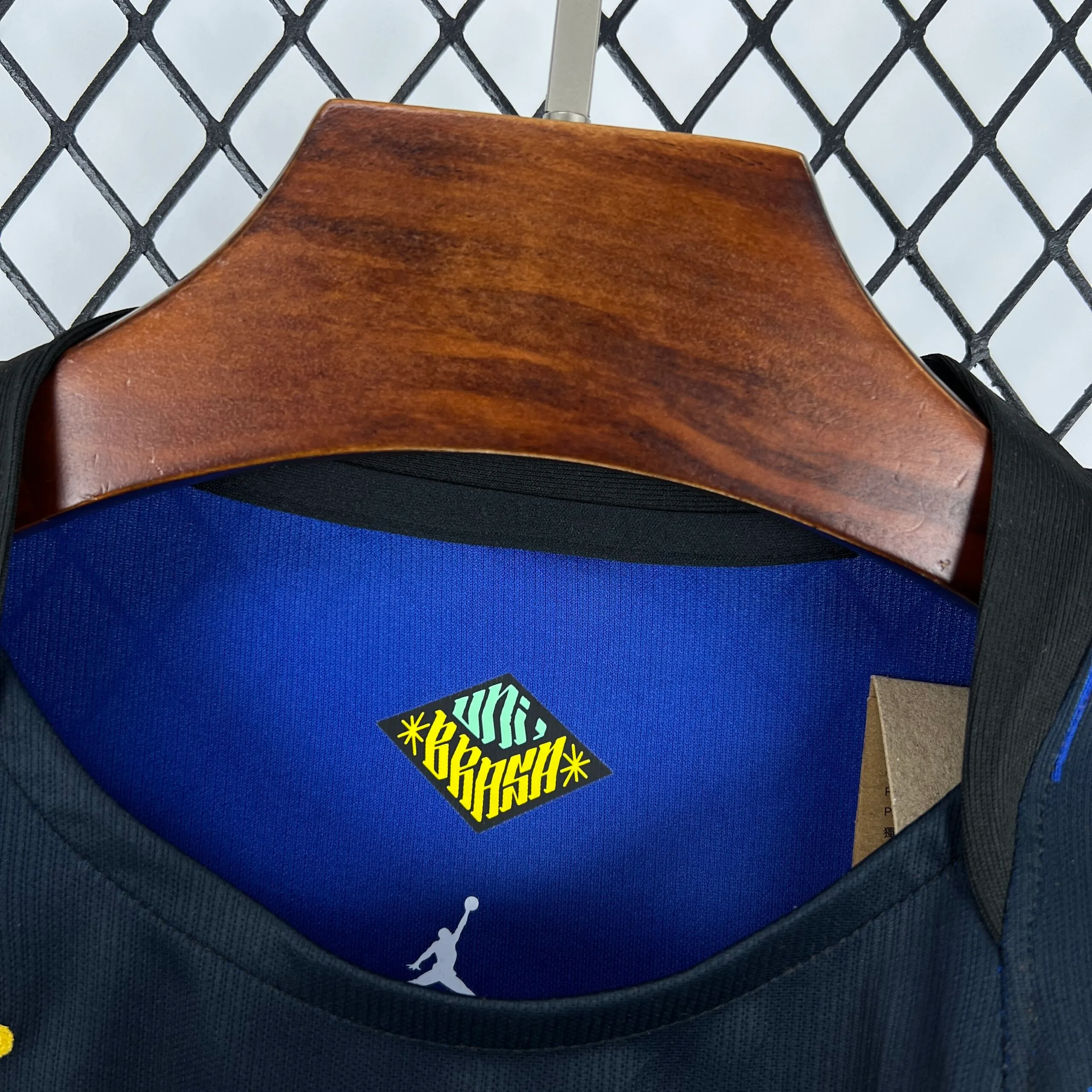 Detalle del cuello redondo azul y verde con logotipos técnicos impresos en el interior de la prenda.