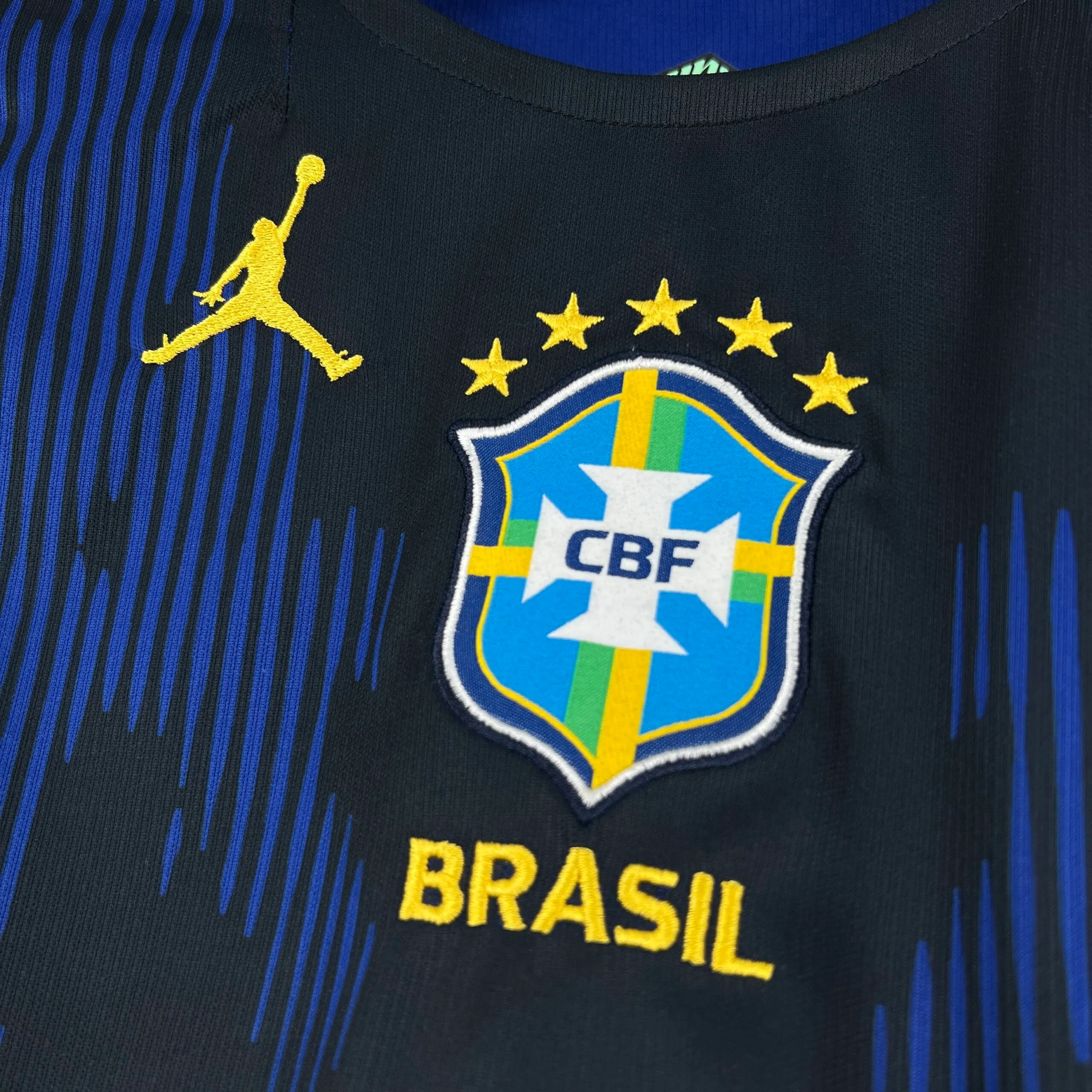 Detalle del escudo de la Confederación Brasileña de Fútbol (CBF) bordado en el centro sobre el patrón gráfico.