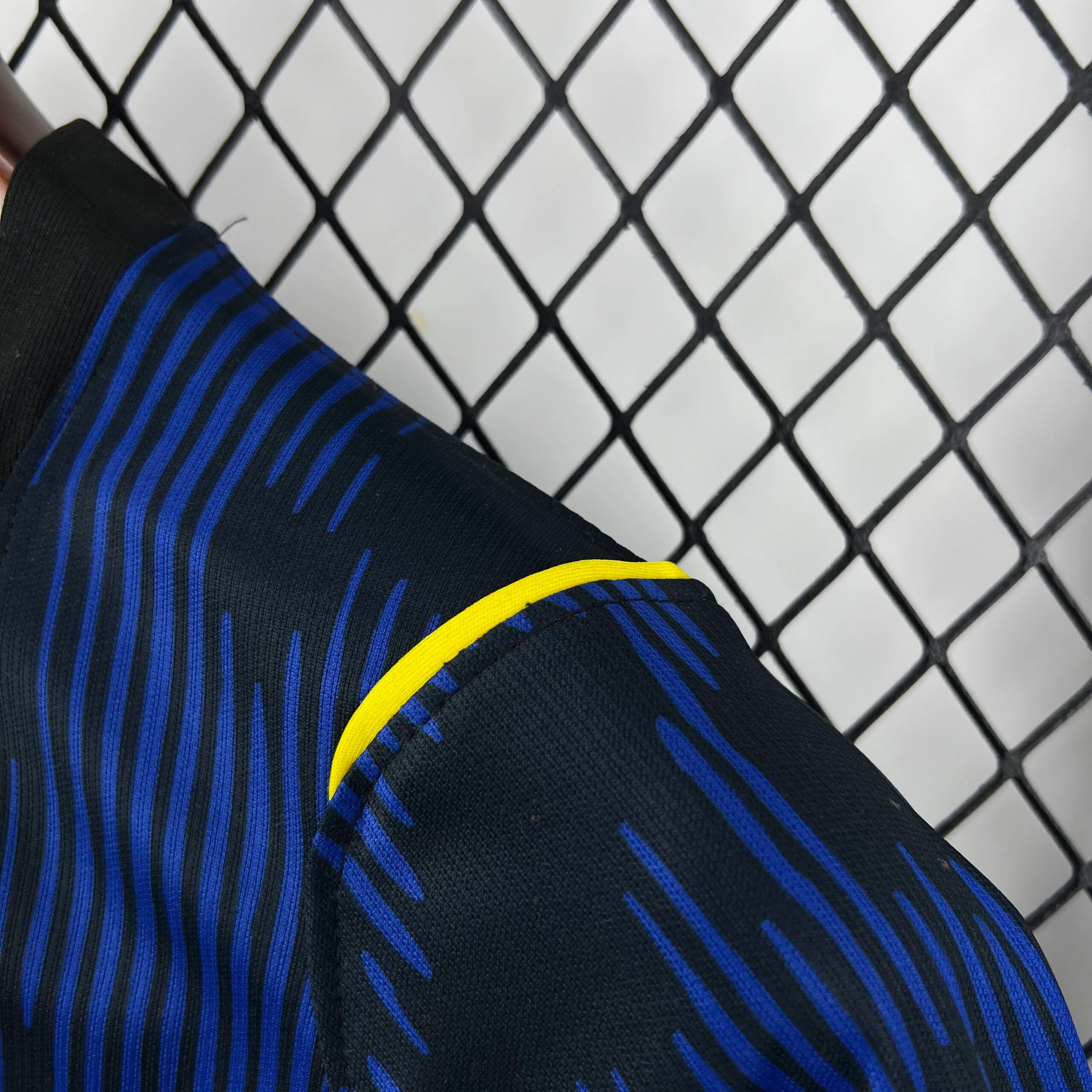 Primer plano del hombro destacando el diseño de ondas en diferentes tonos de azul de la camiseta de Brasil.