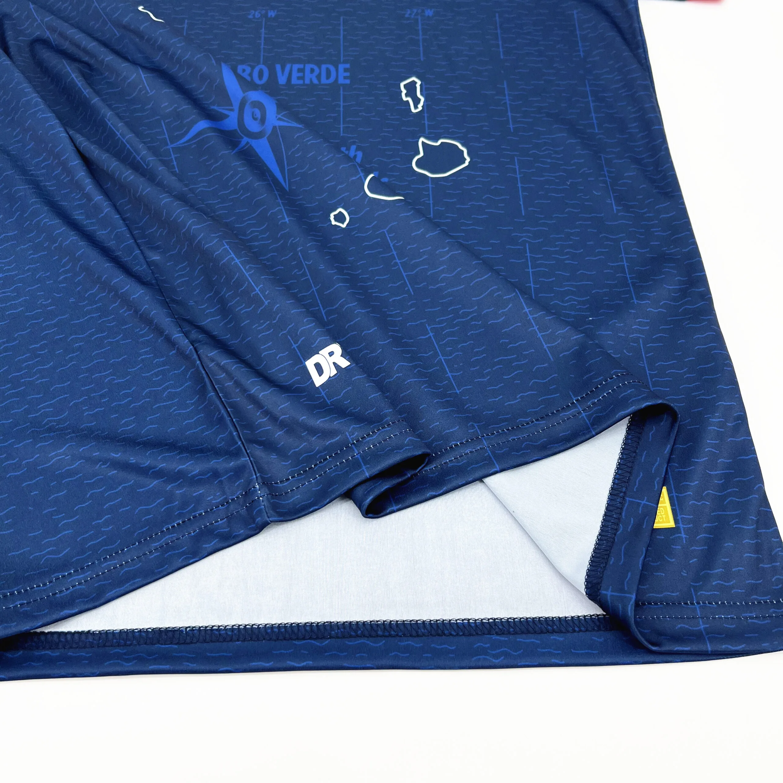 Detalle de la parte inferior de la camiseta mostrando el mapa de las islas de Cabo Verde y una rosa de los vientos.