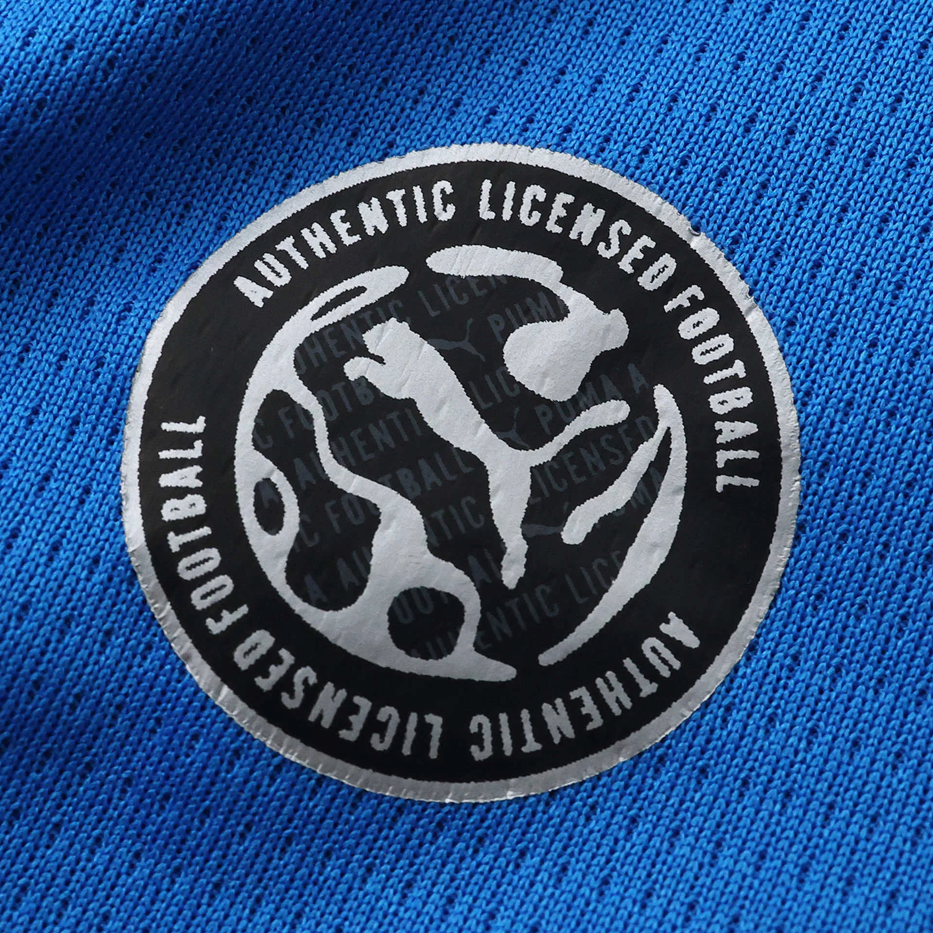 Detalle del parche de autenticidad plateado sobre el tejido azul transpirable de Islandia.