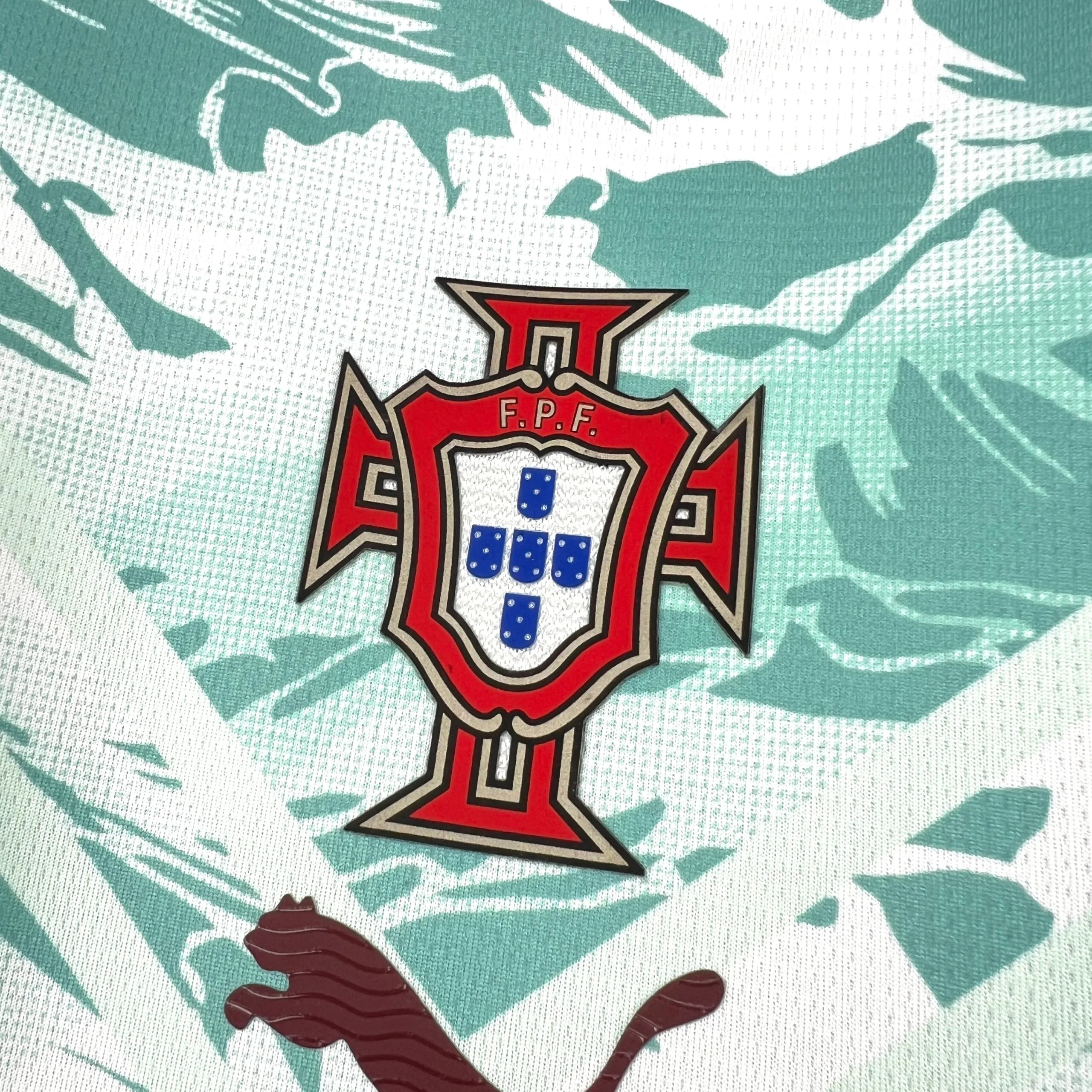 Primer plano del escudo de la Federación Portuguesa de Fútbol (FPF) bordado sobre el diseño de mosaico.