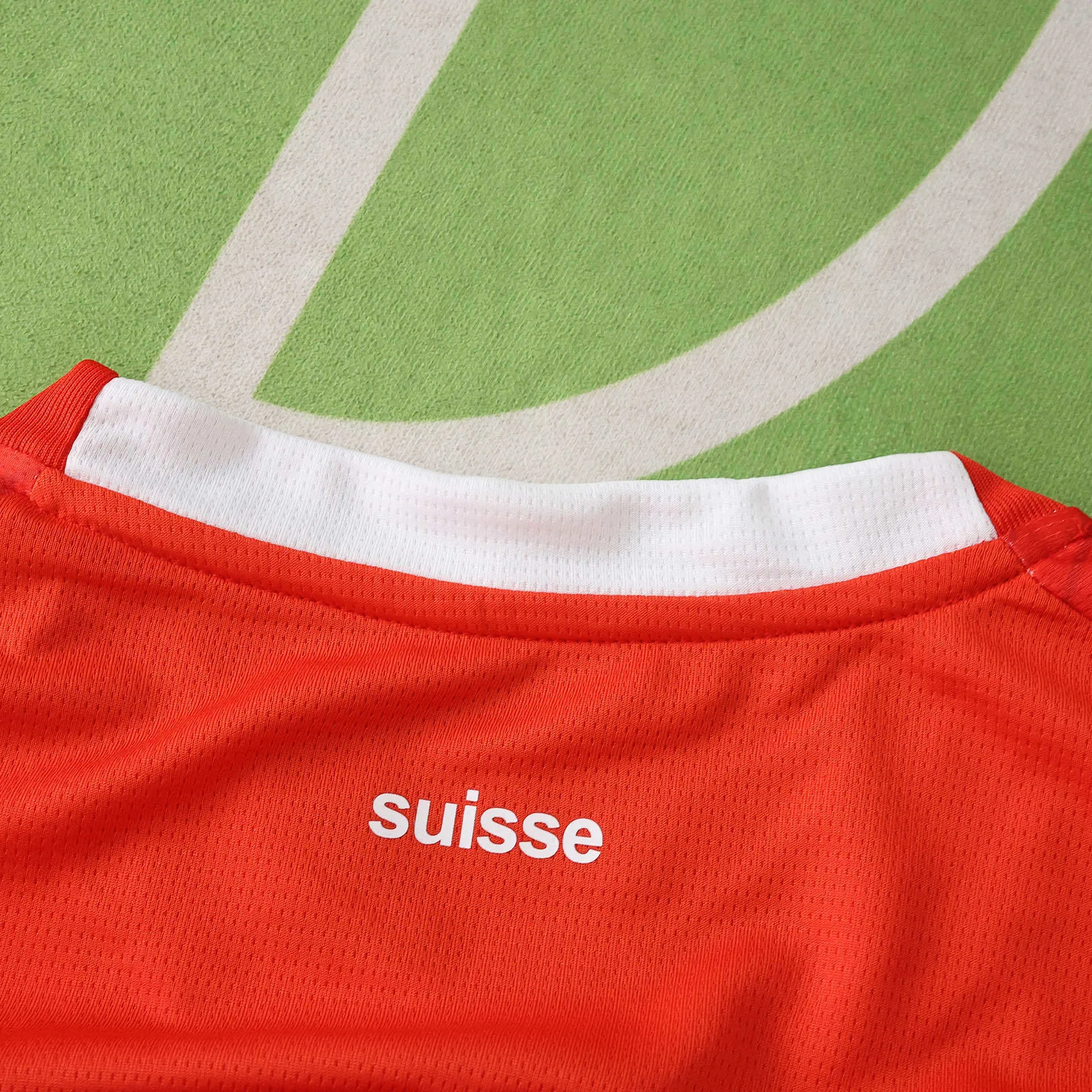 Detalle de la parte posterior del cuello de la camiseta de Suiza con la inscripción "suisse" en letras blancas sobre fondo rojo.