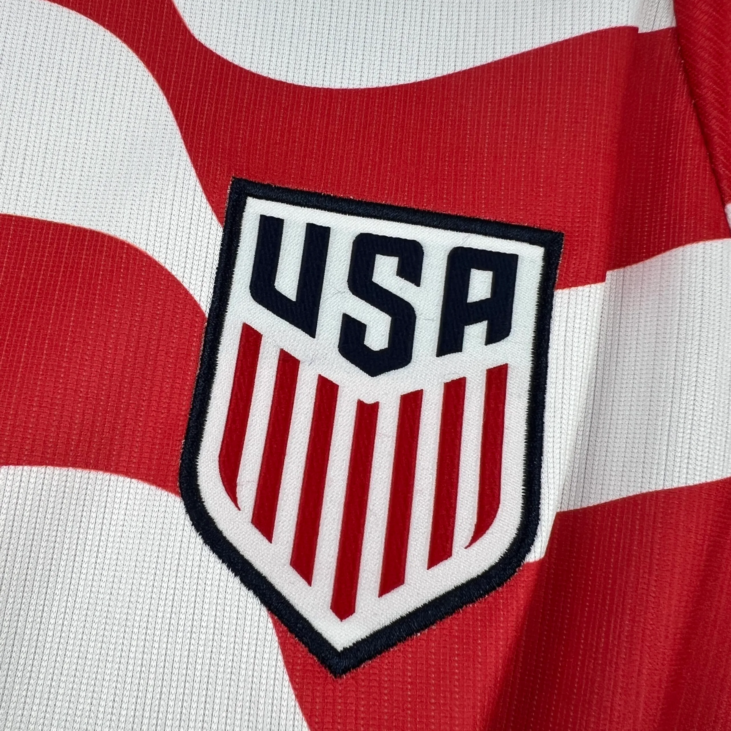 Primer plano del escudo de la federación de fútbol de Estados Unidos (USSF) bordado sobre el fondo azul degradado.