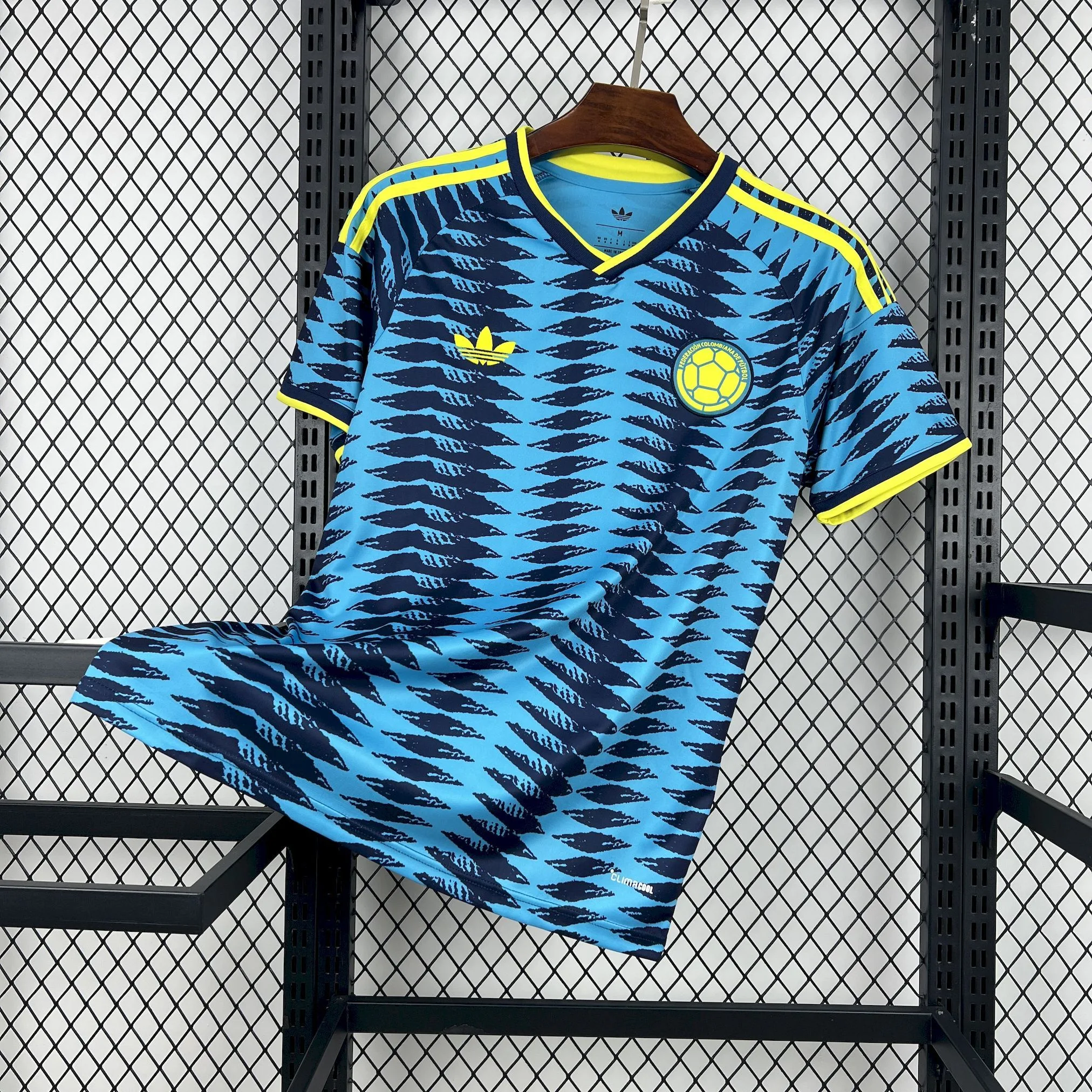 Imagen frontal completa de la camiseta visitante de Colombia para el Mundial 2026, en color negro con detalles laterales en naranja vibrante.
