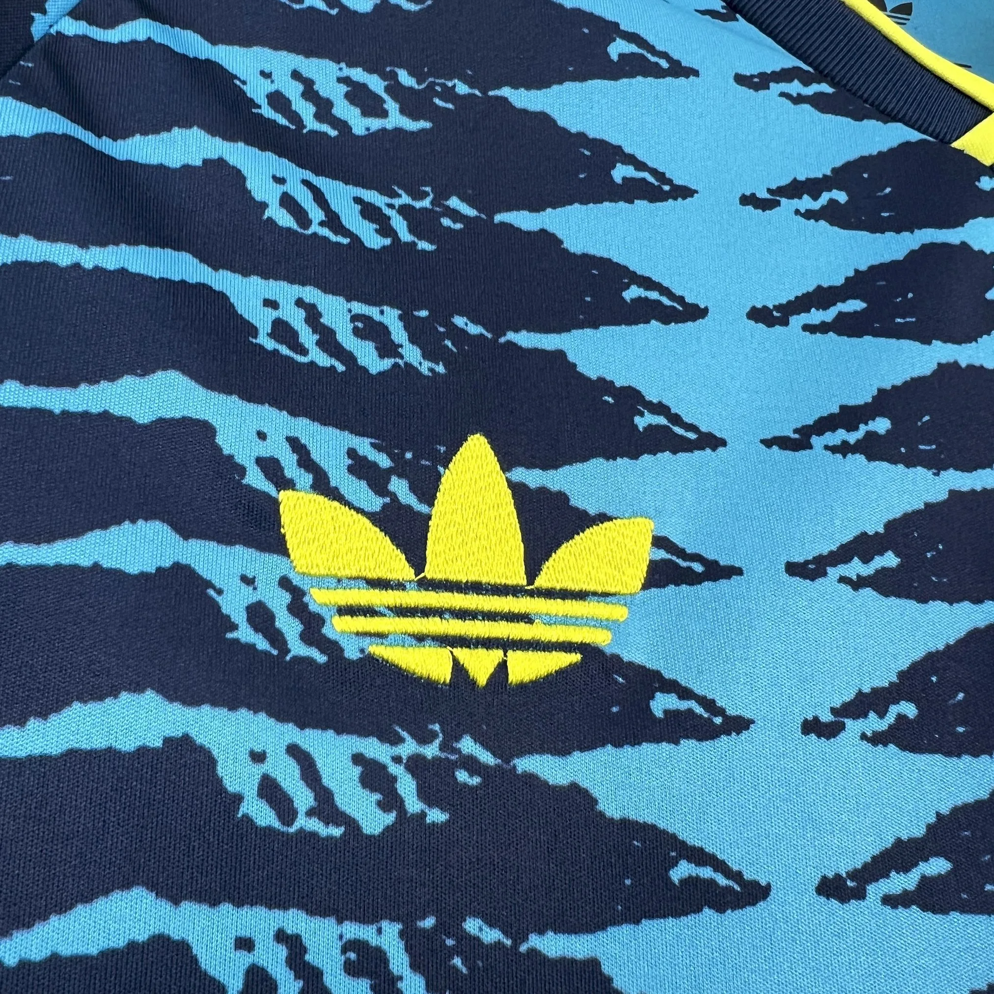 Detalle decorativo bordado en color naranja sobre el pecho de la camiseta de la selección de Colombia.