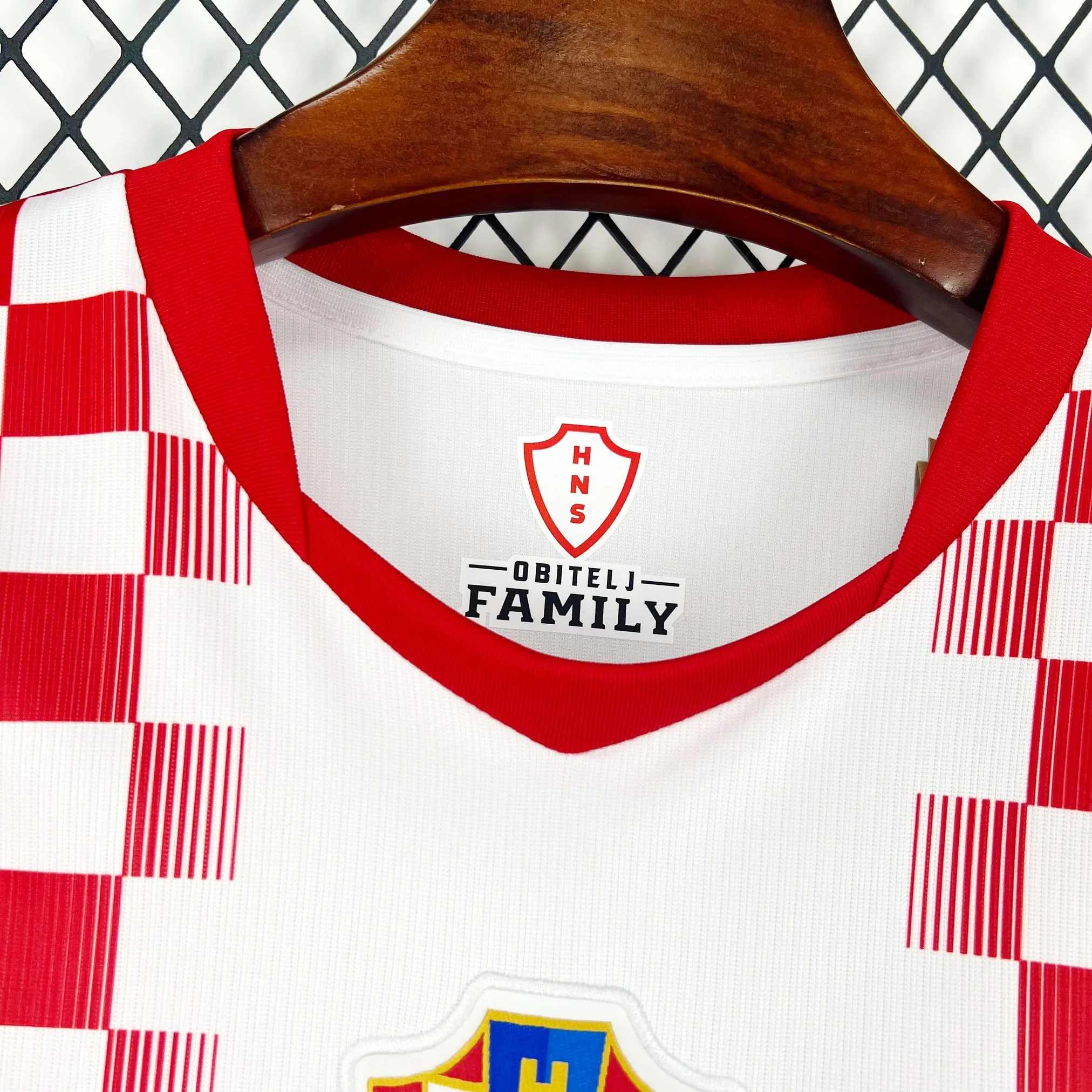 Vista de cerca del cuello redondo de la camiseta de la selección de Croacia, con un ribete frontal en color rojo. En el interior blanco, se observa el logotipo de la marca, la tecnología "AERO-FIT", la talla "M" y la información de fabricación en Tailandia.