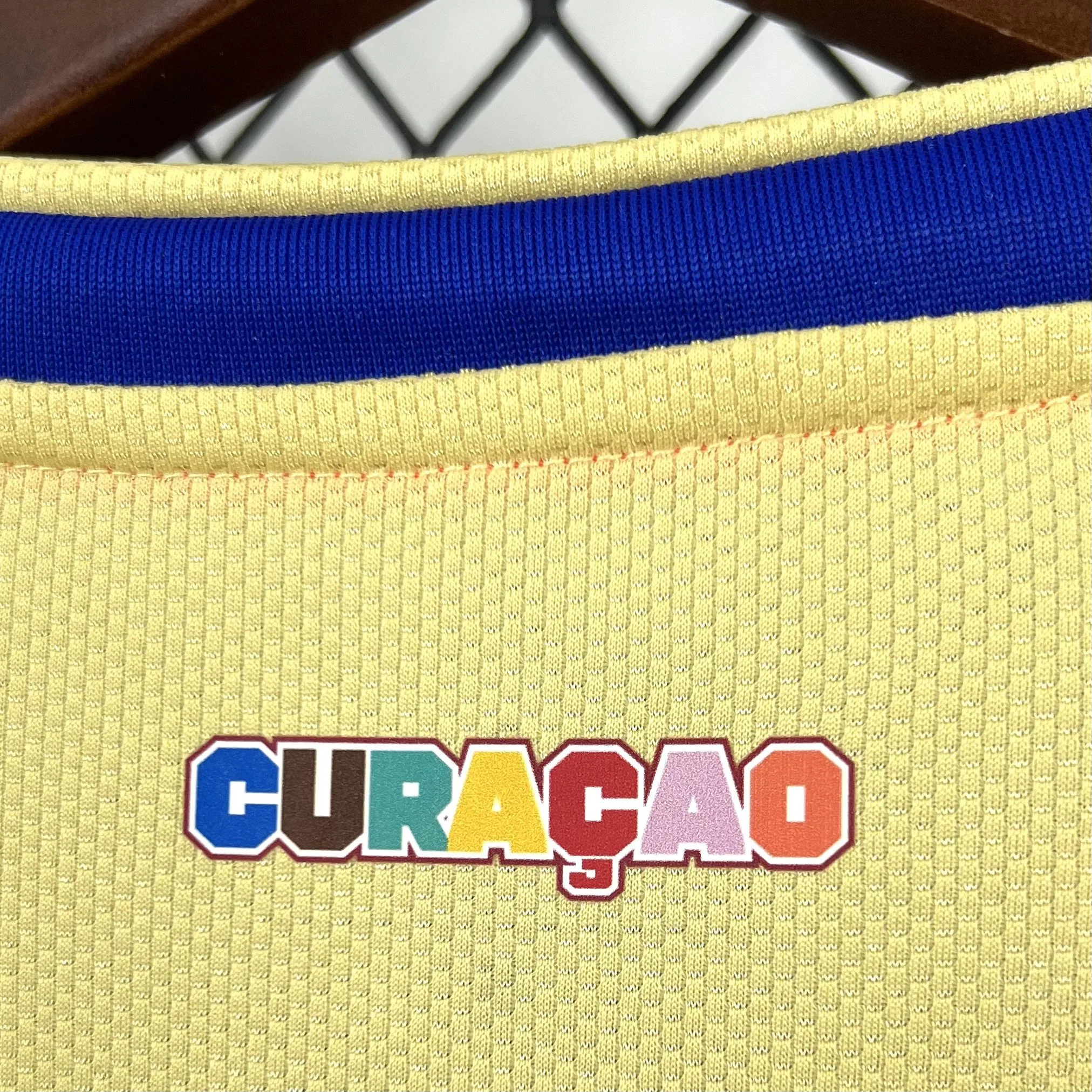 Vista posterior del cuello blanco resaltando el ribete amarillo y azul, y la textura transpirable del material.