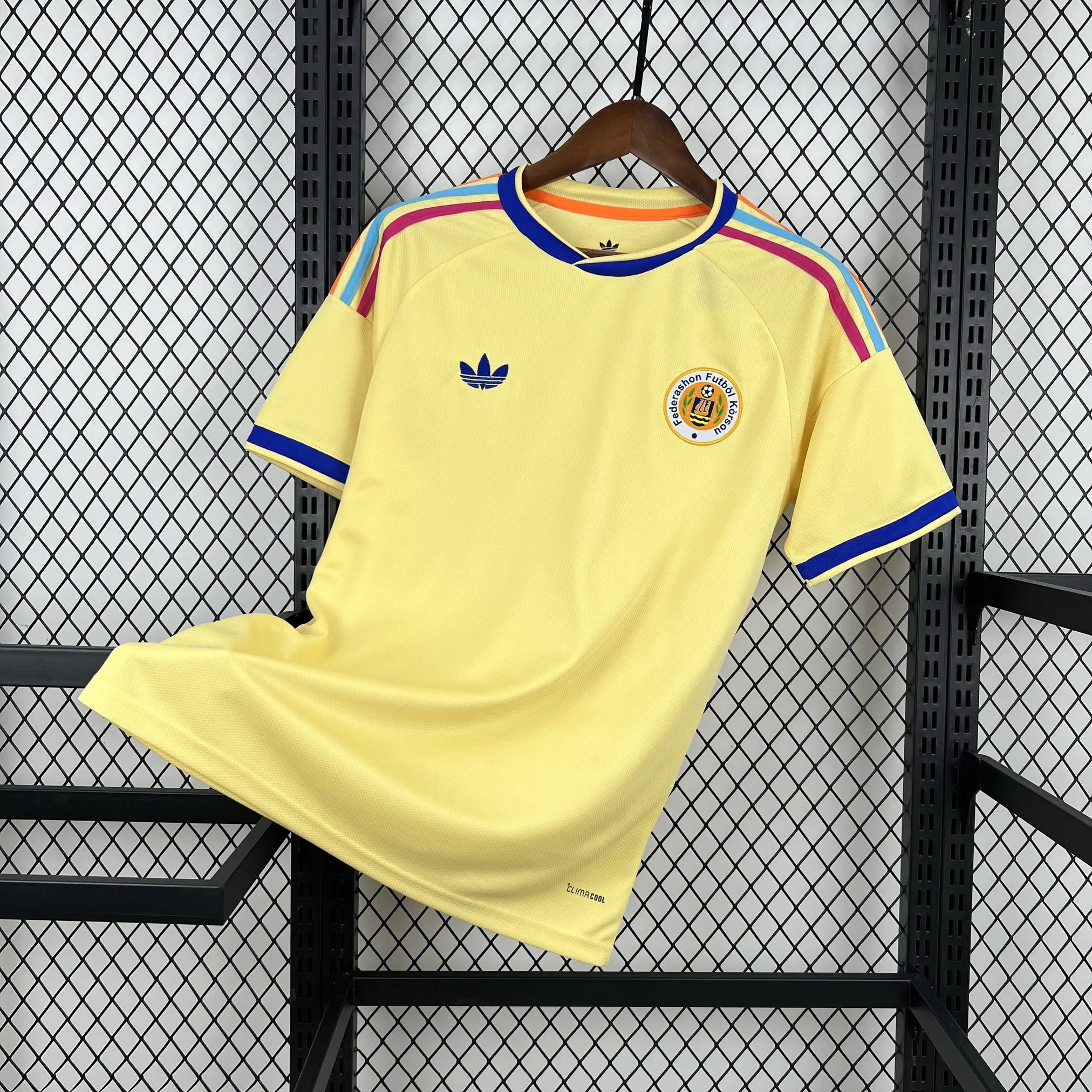 Imagen frontal completa de la camiseta de Curazao visitante, color blanco con un patrón gráfico de mosaicos culturales grises en el torso.