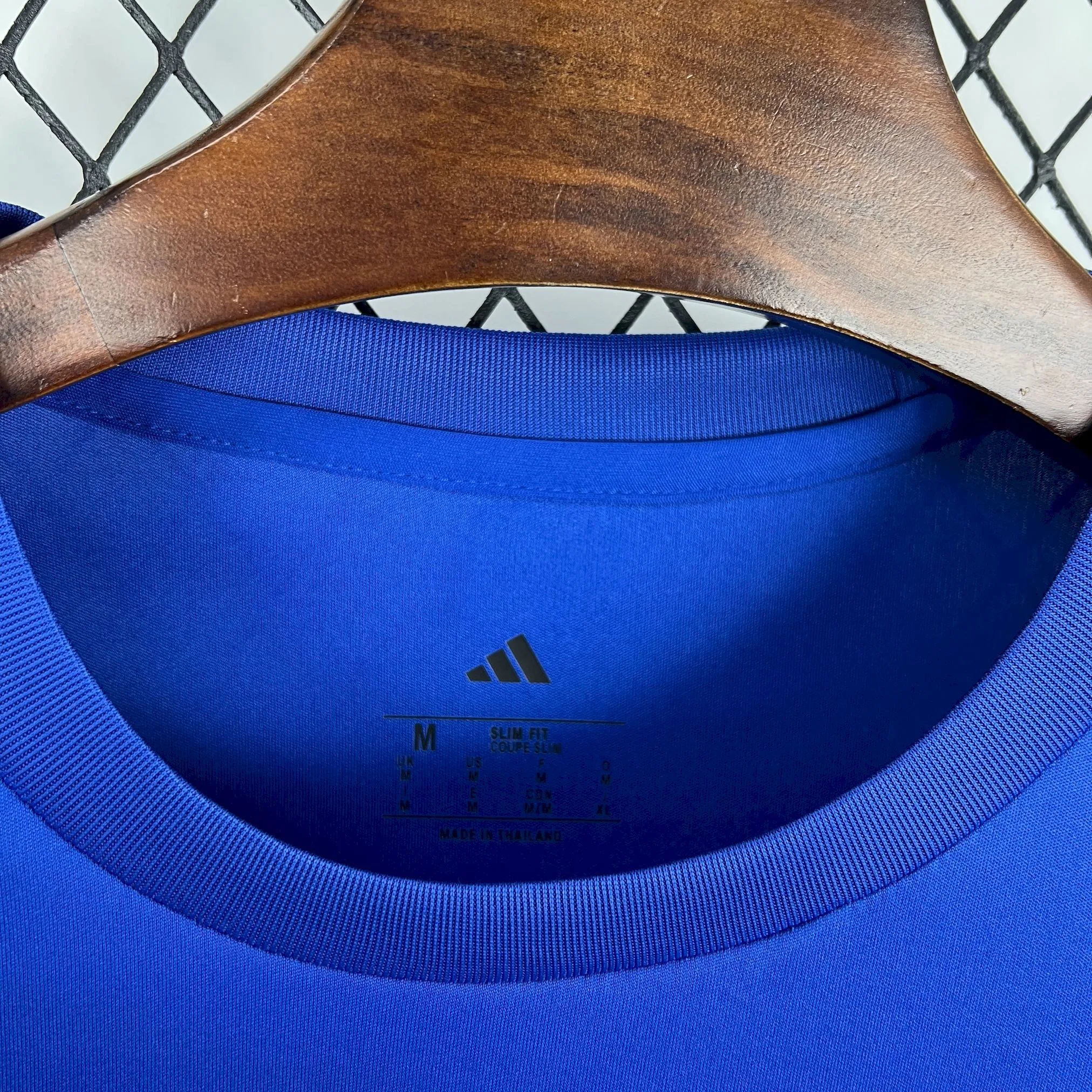 Detalle del cuello redondo azul con ribetes amarillos y logotipos de tecnología impresos en el interior.