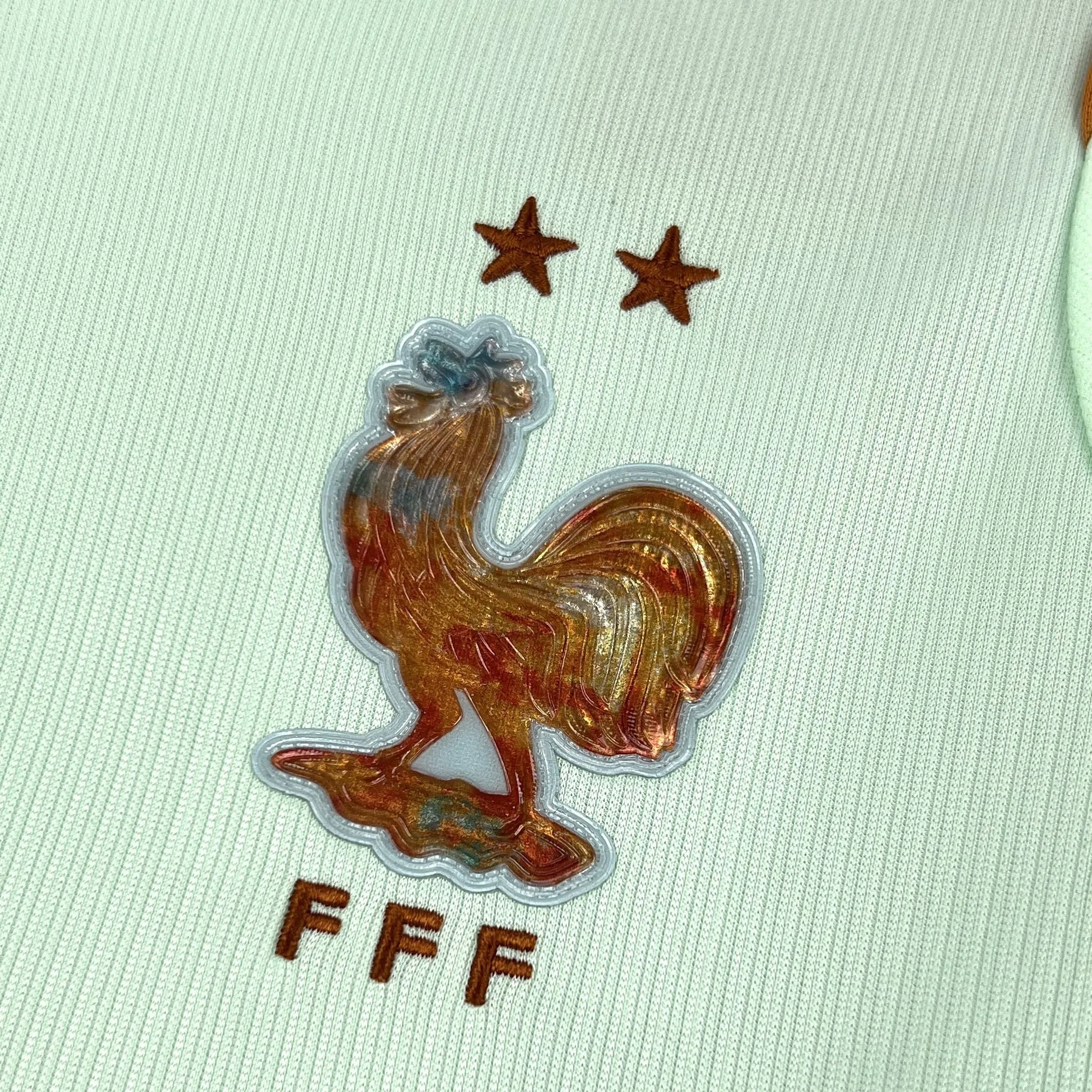 Primer plano del escudo del gallo de la selección francesa bordado en color azul sobre el fondo blanco.