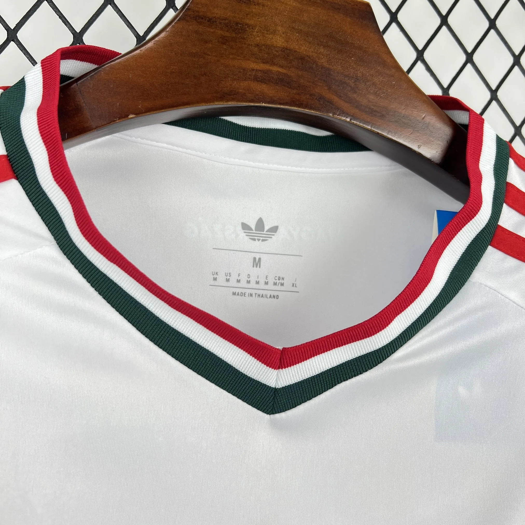 Detalle del cuello redondo de la camiseta visitante de Hungría en color blanco con finos vivos en rojo y verde.