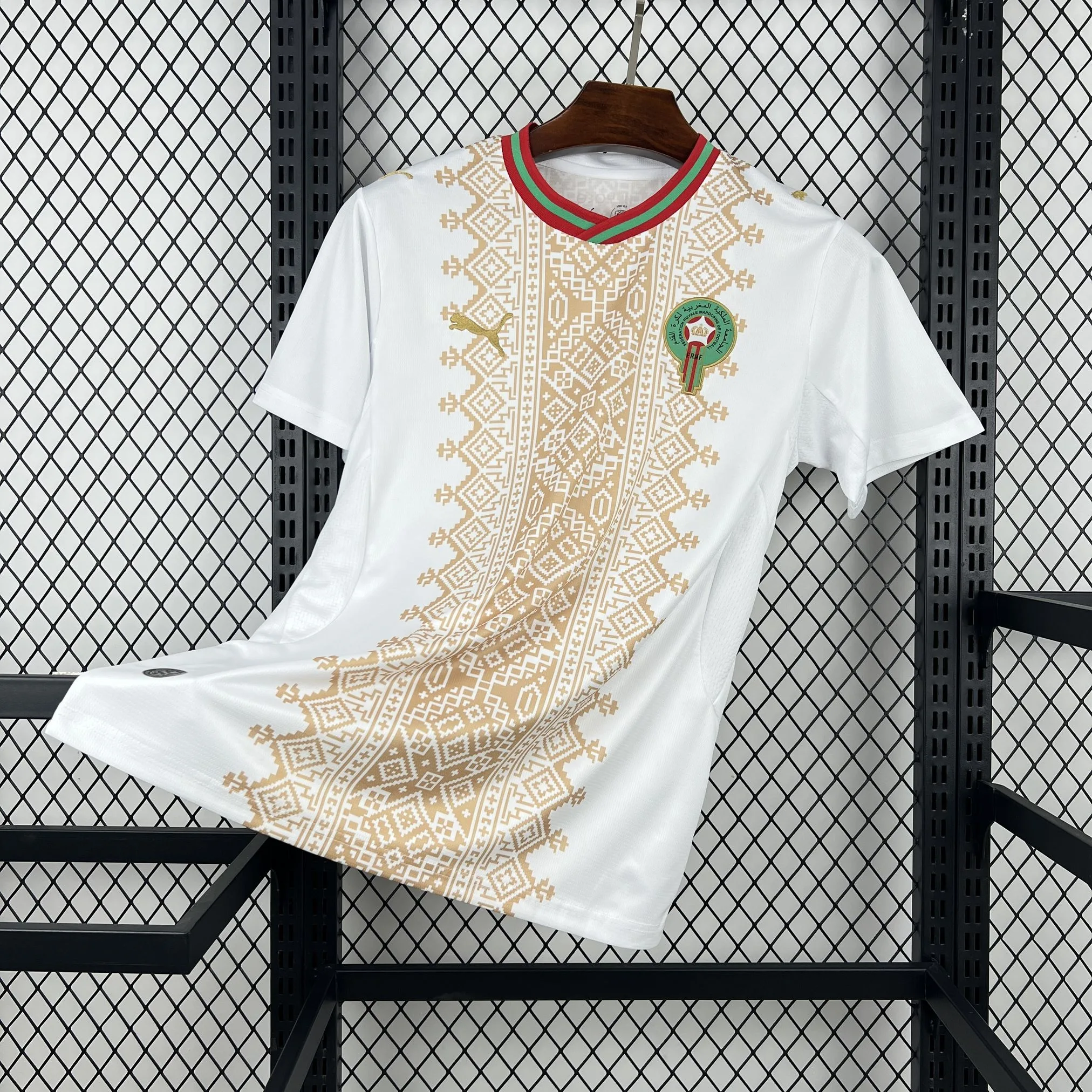 Imagen frontal completa de la camiseta de Marruecos visitante, blanca con un gráfico central inspirado en la artesanía marroquí.