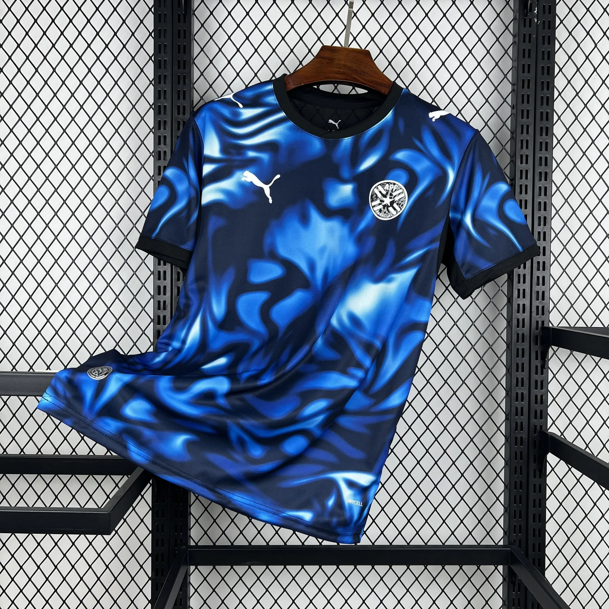 Imagen frontal completa de la camiseta visitante de Paraguay, color azul con un patrón gráfico de ondas tonales inspiradas en la naturaleza.