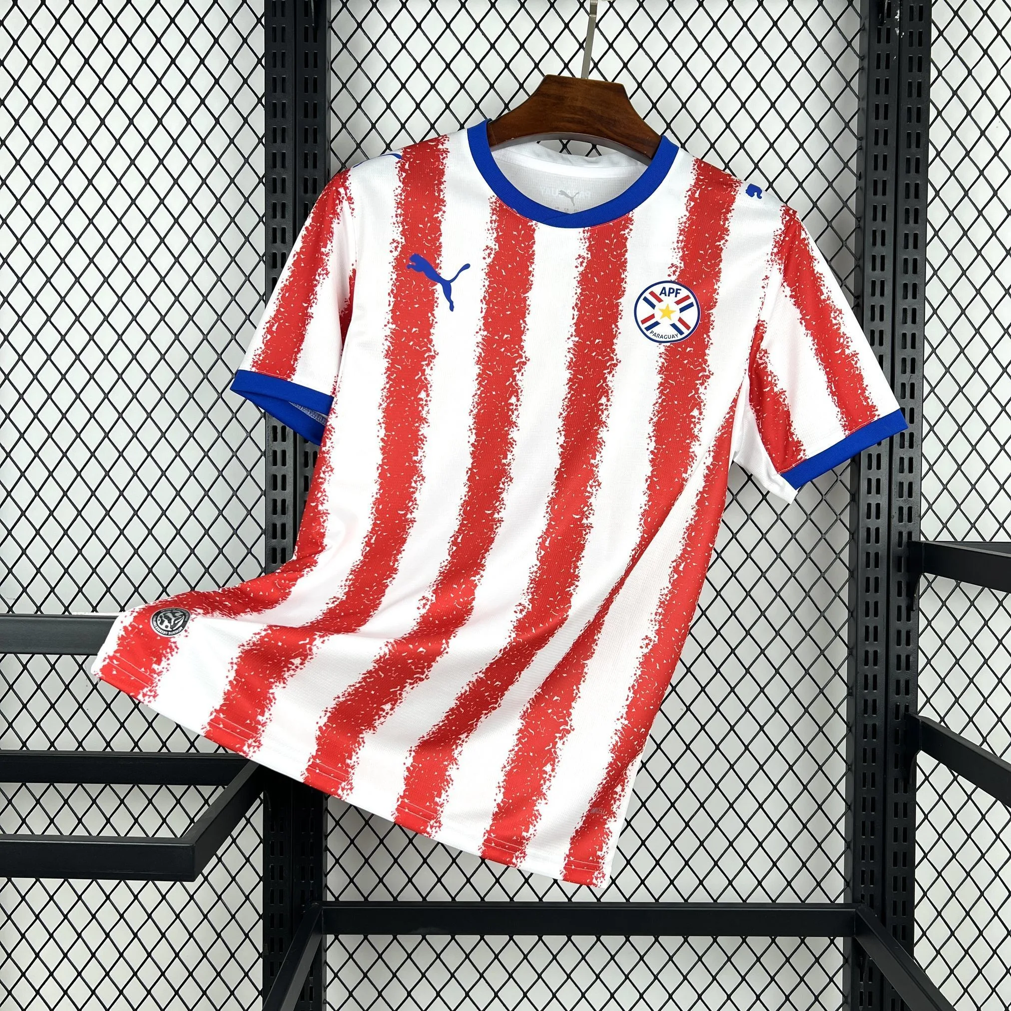 Imagen frontal completa de la camiseta de Paraguay 2026, diseño clásico de franjas verticales rojas y blancas con detalles azules.