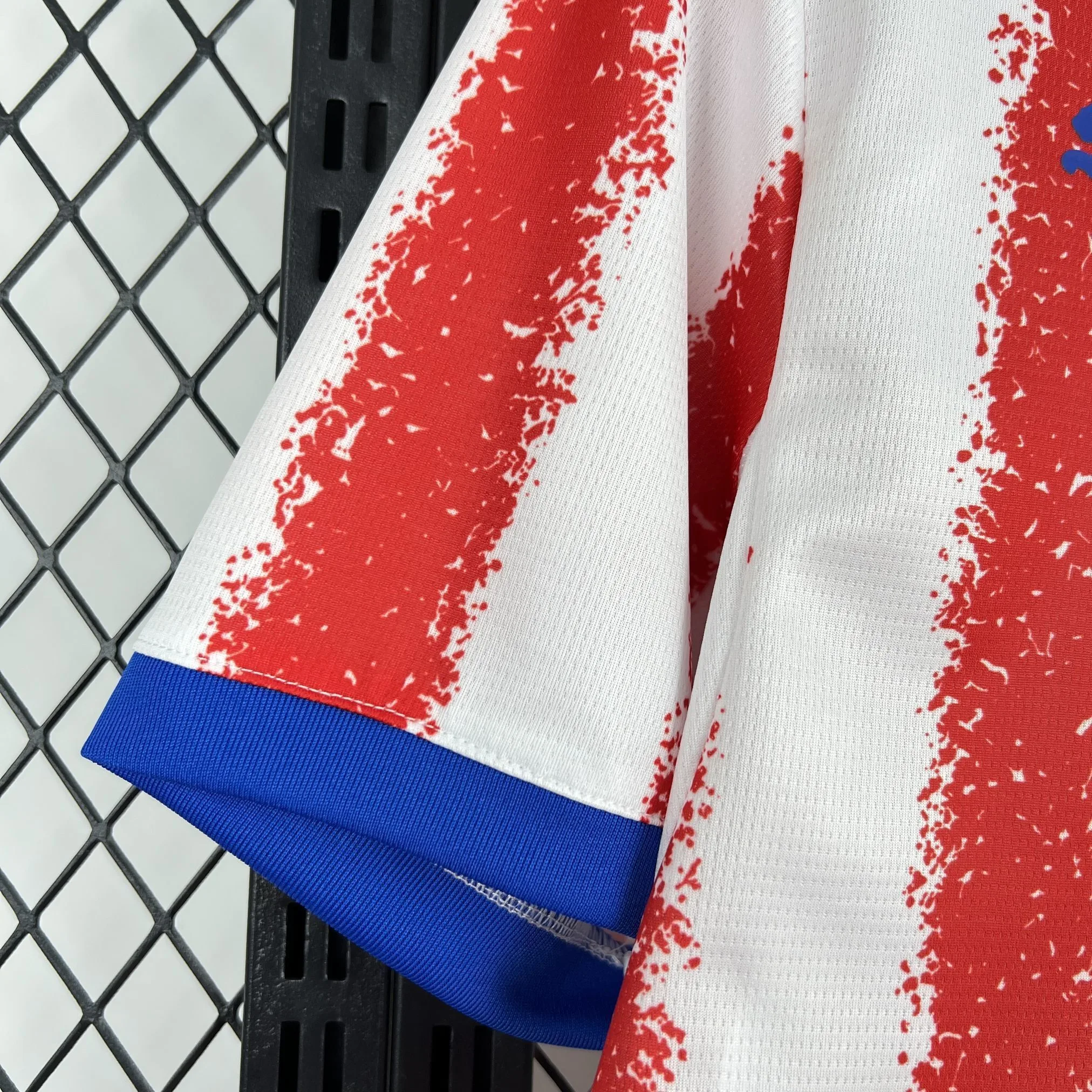 Detalle de la manga con franjas verticales rojas y blancas, y remate elástico en color azul marino.
